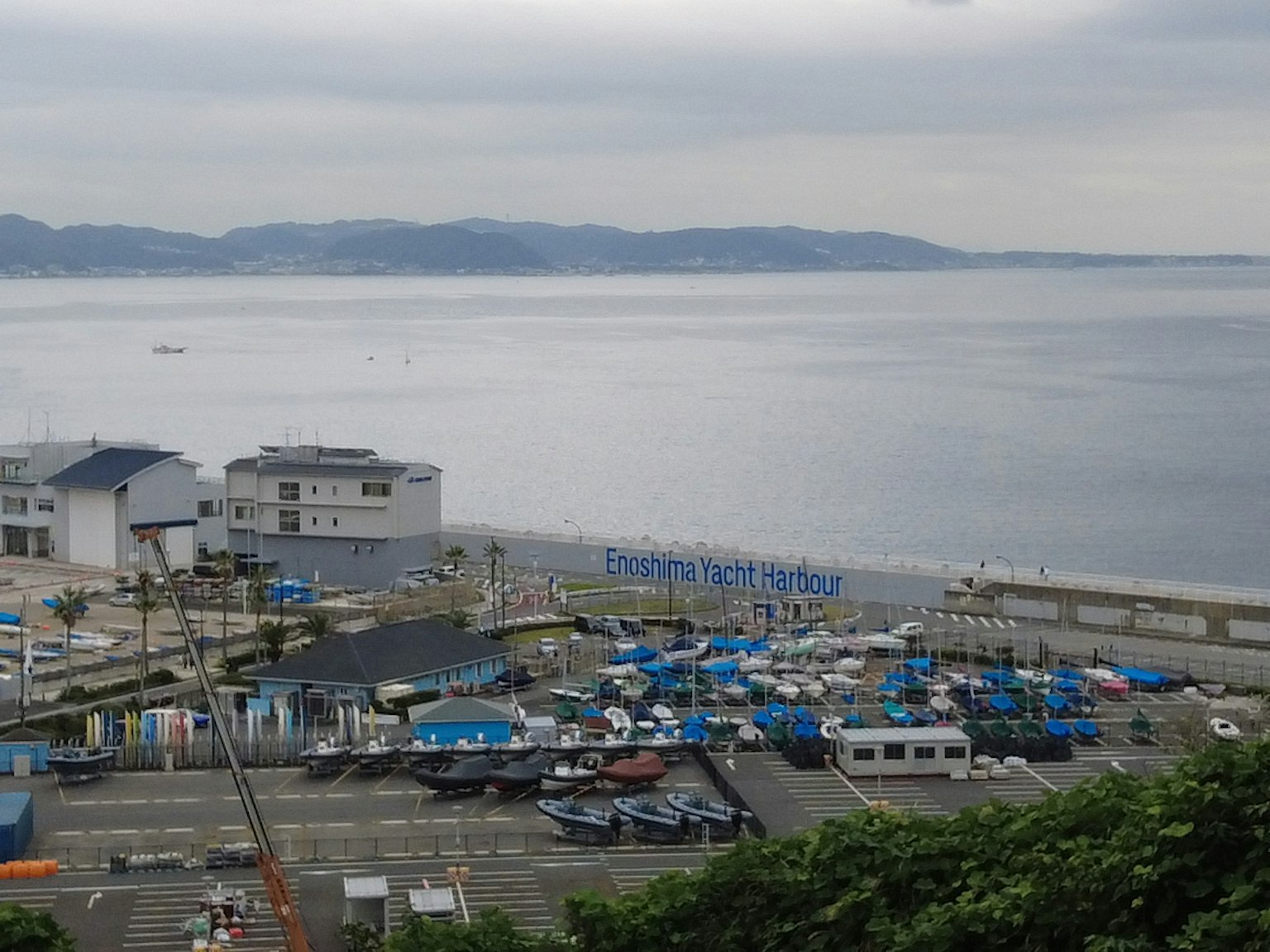 Vista sul mare calmo e fabbrica con barche ormeggiate nel porto