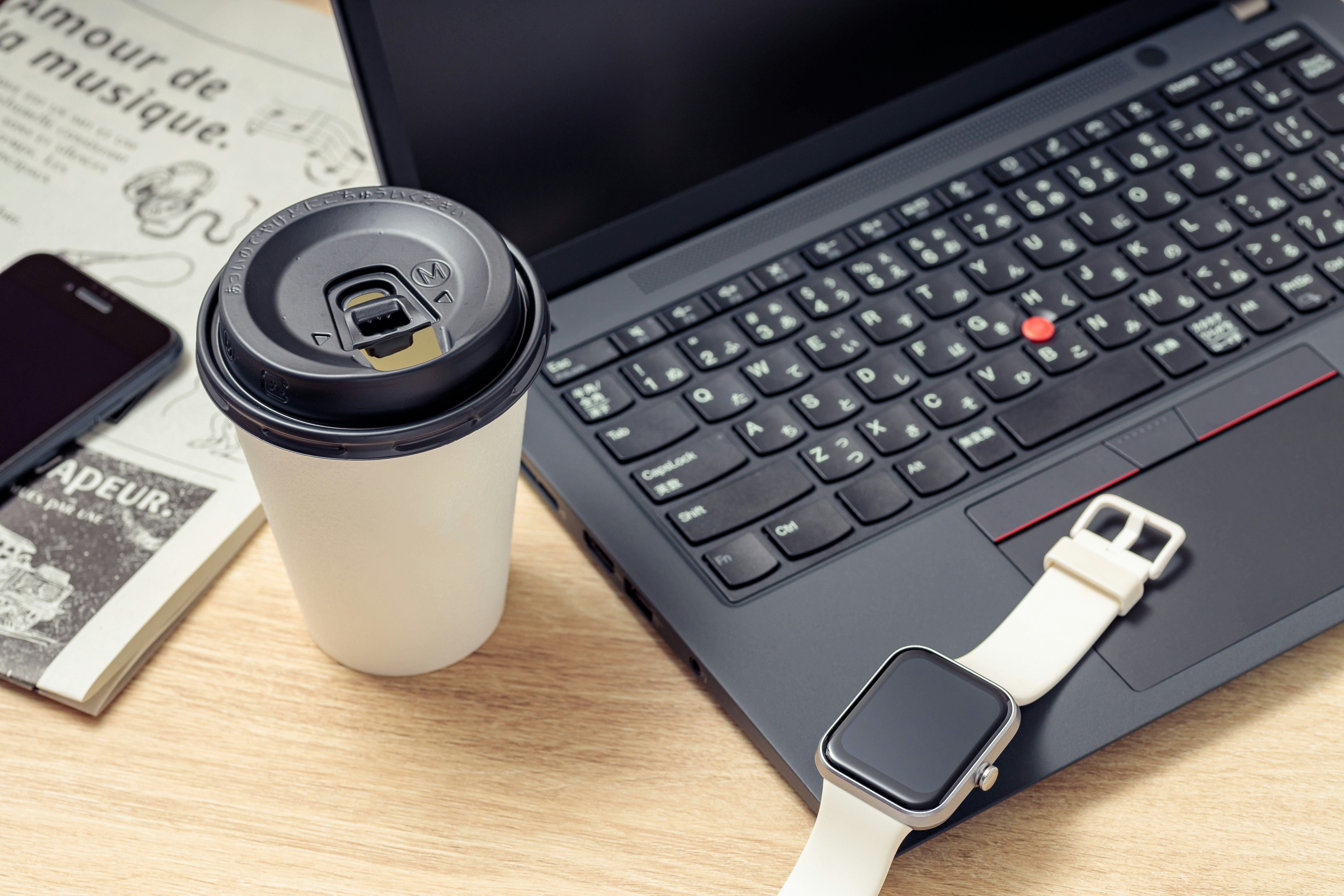 ノートPCとスマートウォッチ、コーヒー缶のあるデスク