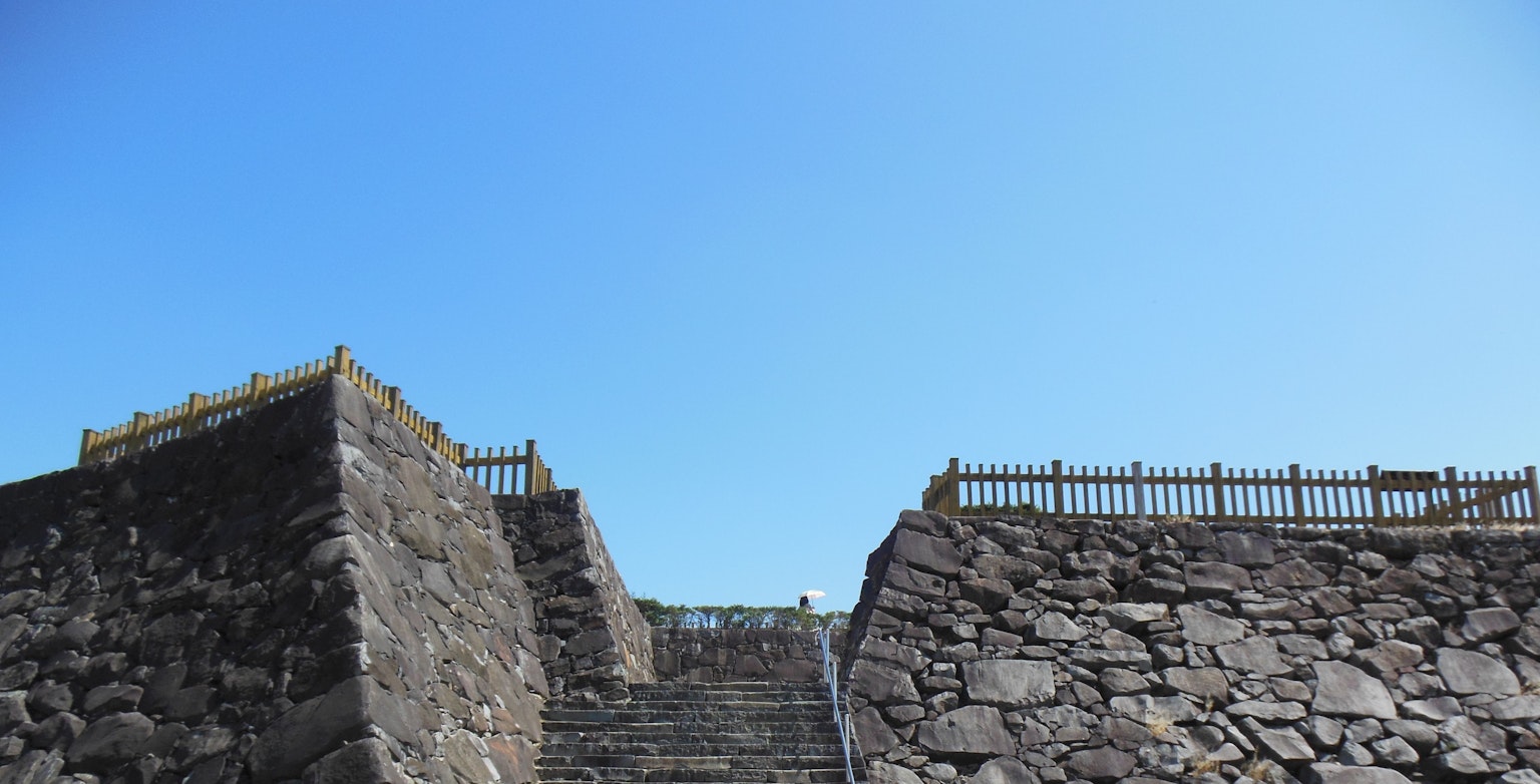 Escaliers en pierre menant à une fortification sous un ciel bleu clair