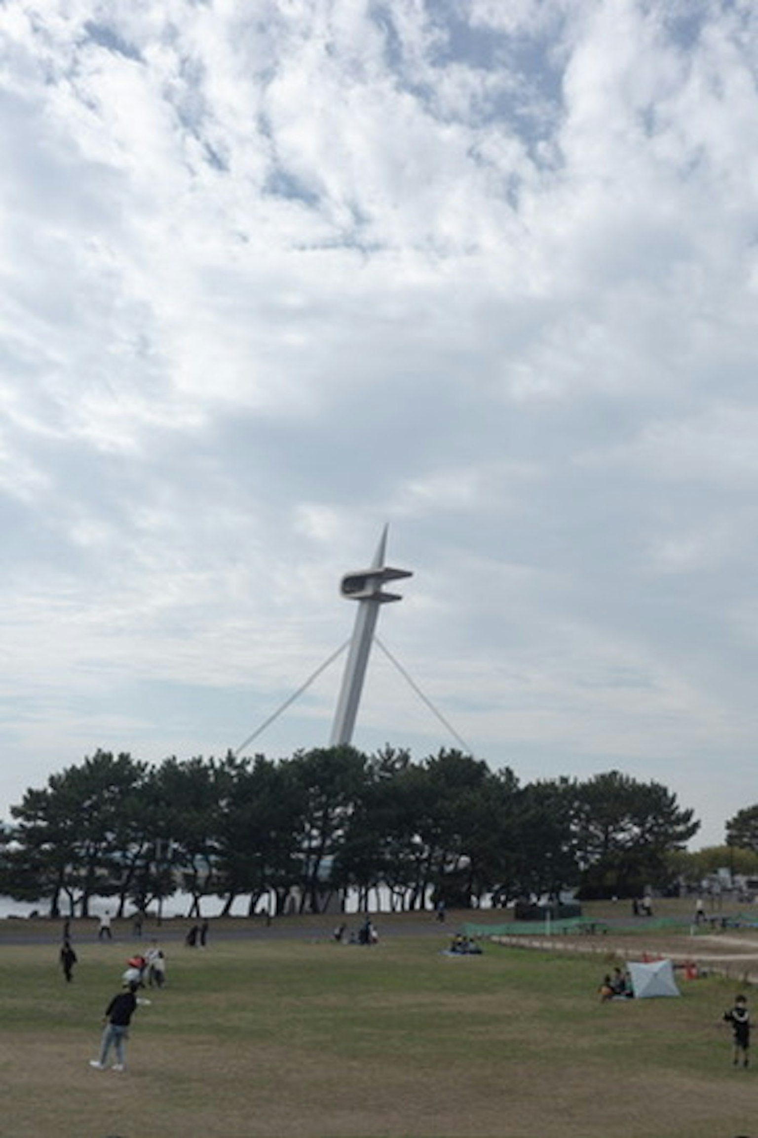 Menara tinggi dengan struktur berputar di belakang pohon hijau