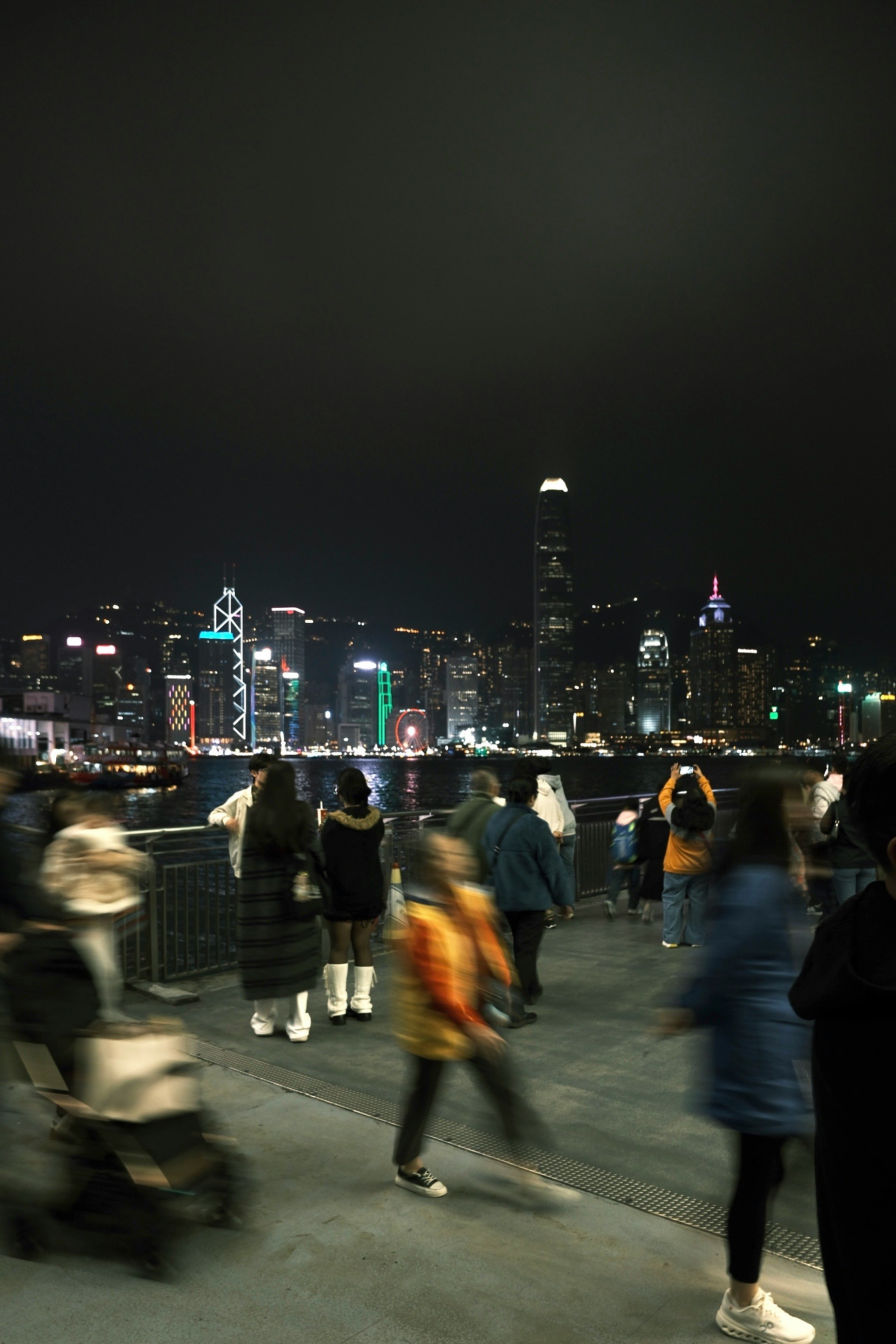 夜の香港のビクトリアハーバーを背景にした人々の群れ