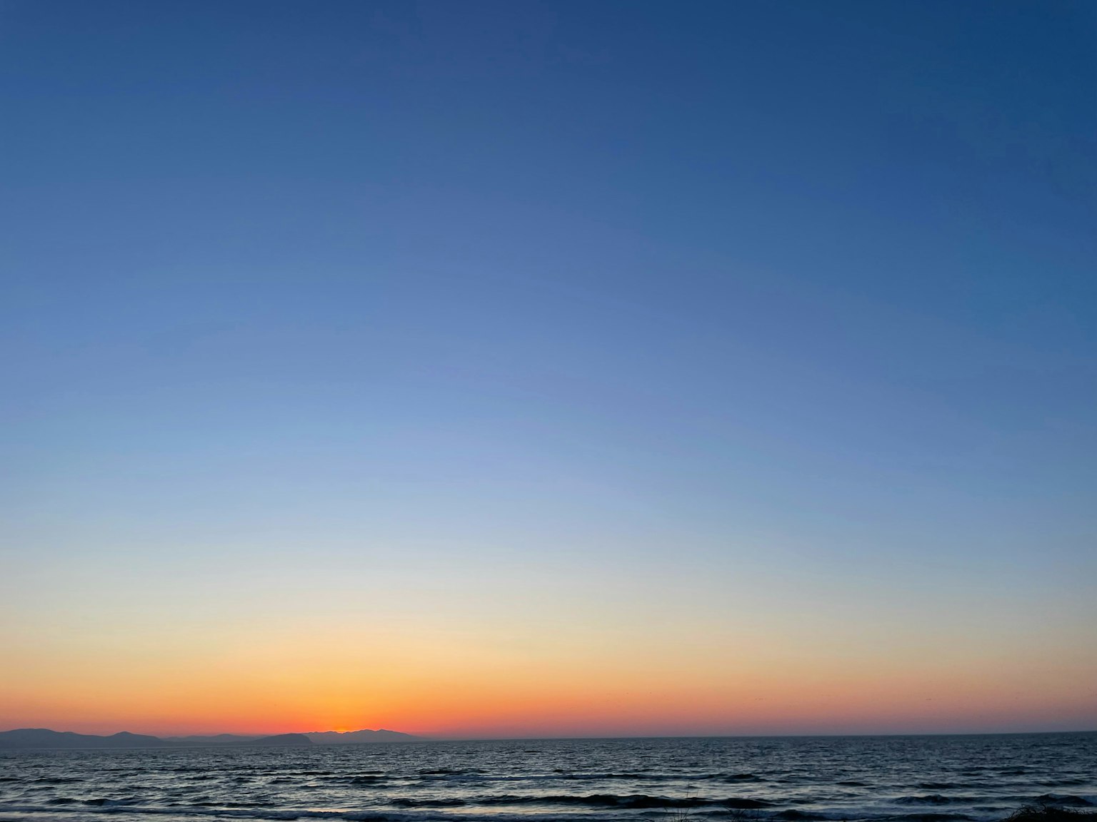 Paysage maritime au coucher du soleil avec ciel bleu et dégradé orange