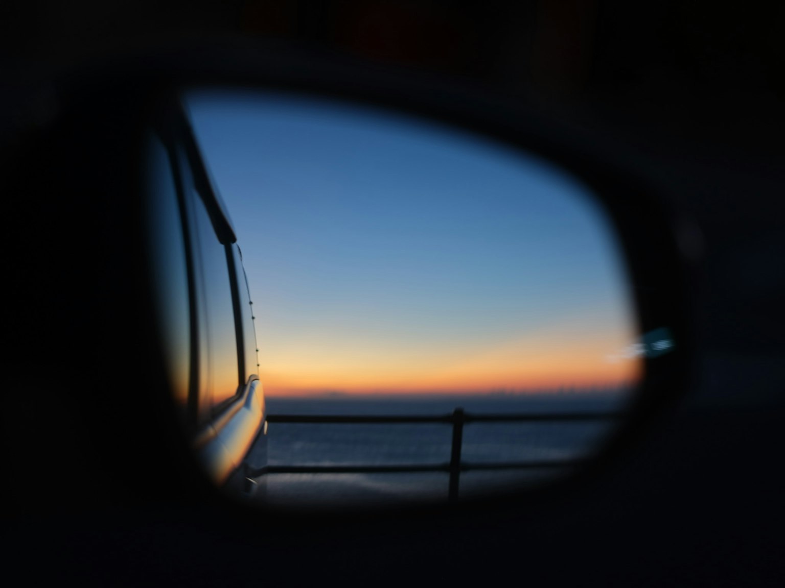 車のサイドミラーに映る夕焼けの景色