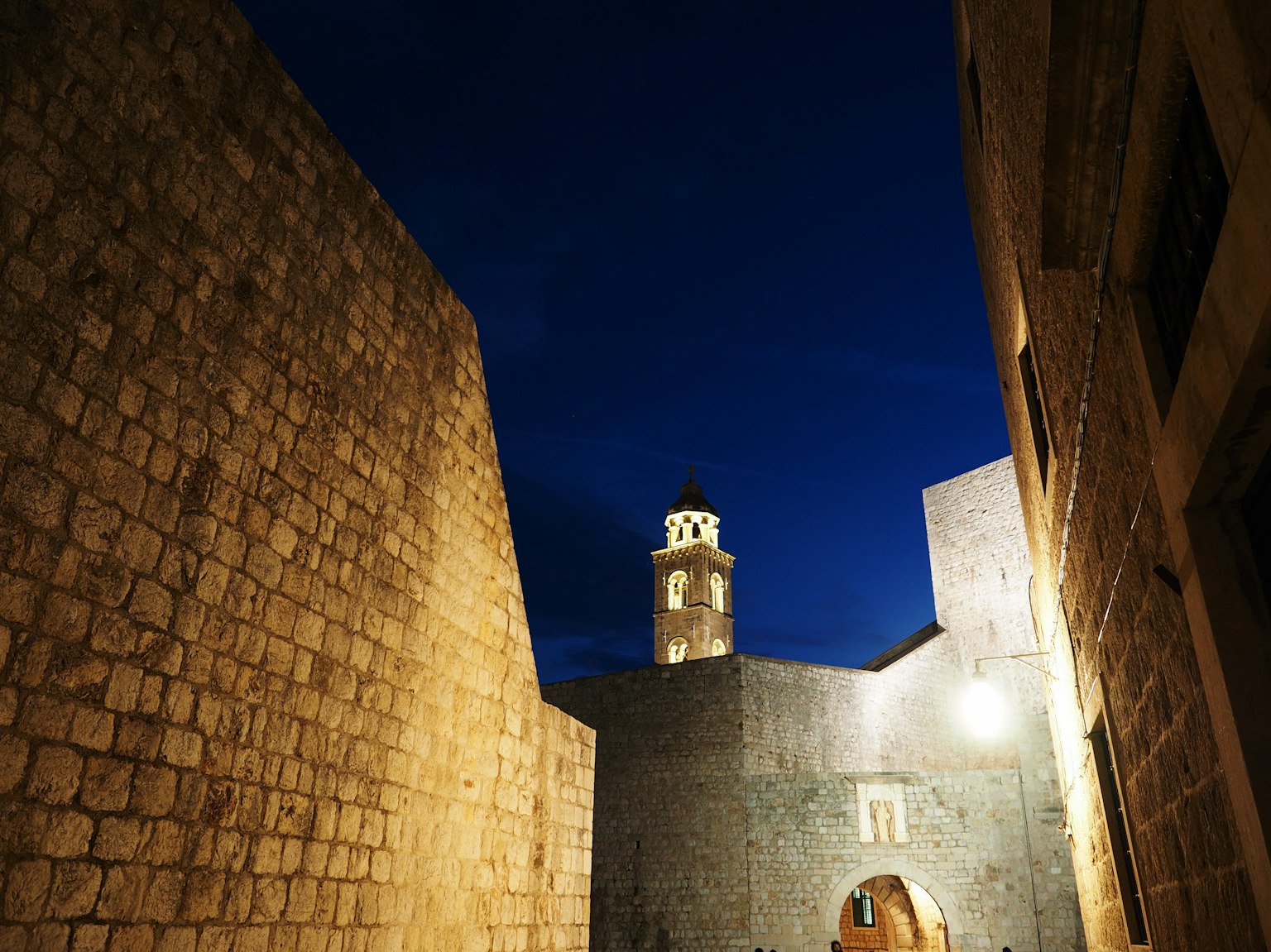 Muri in pietra antica e una torre in un ambiente notturno scuro