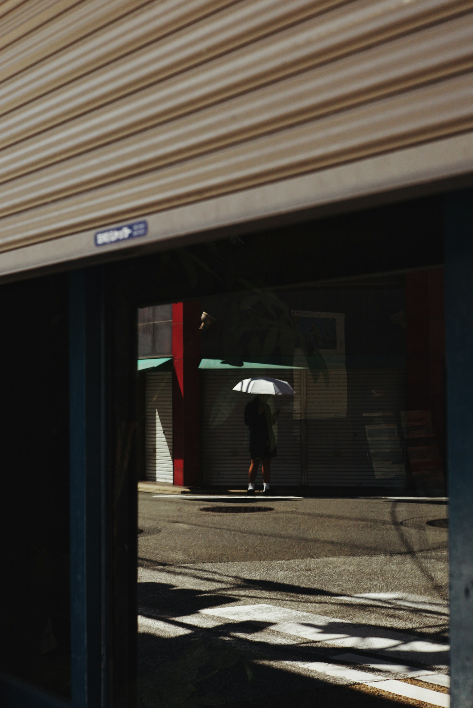 A street scene reflecting a person with an umbrella