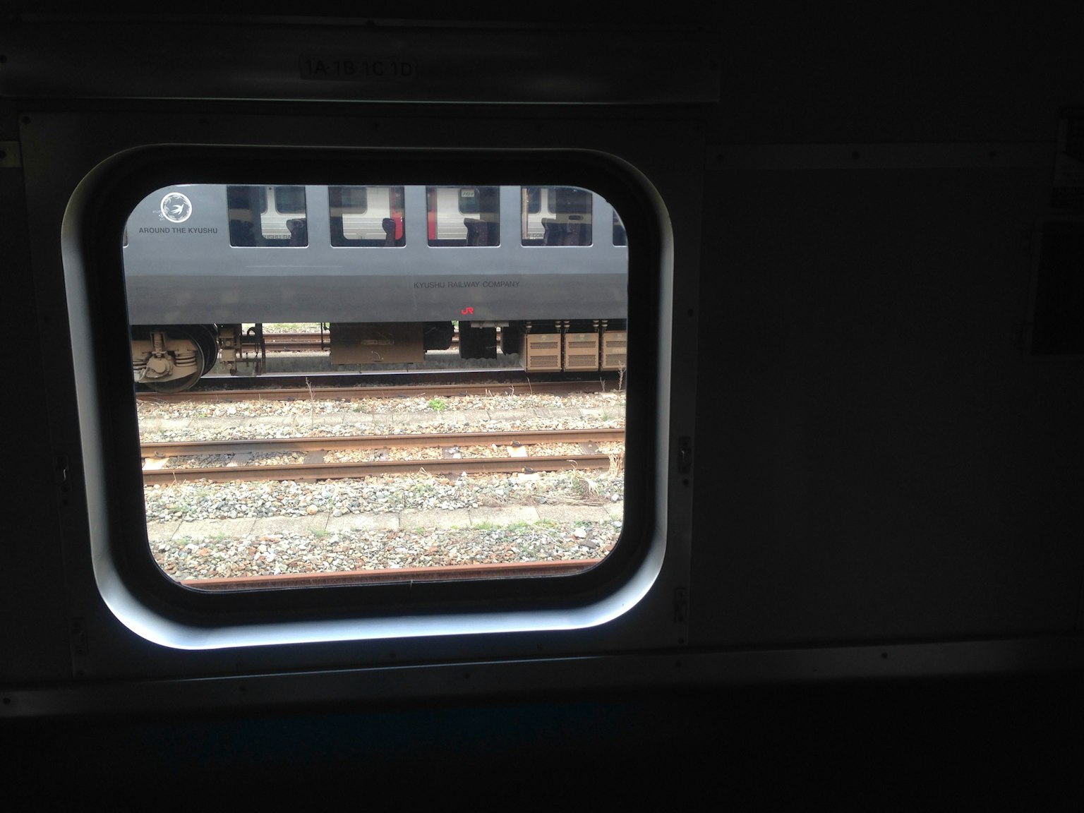 View of railway tracks and adjacent train through a train window