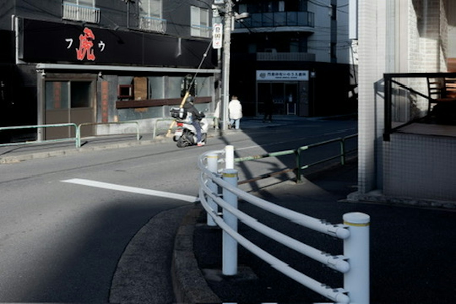 Vue d'un coin de rue avec une rambarde blanche et un magasin