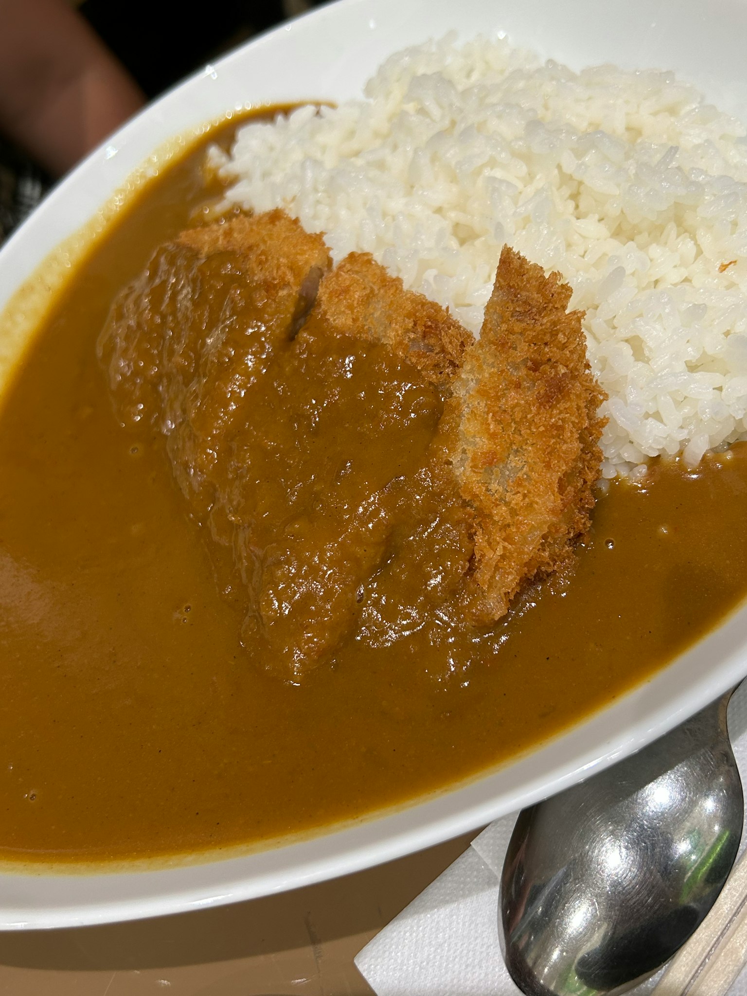 Un plato de arroz al curry con chuleta empanizada y arroz blanco esponjoso