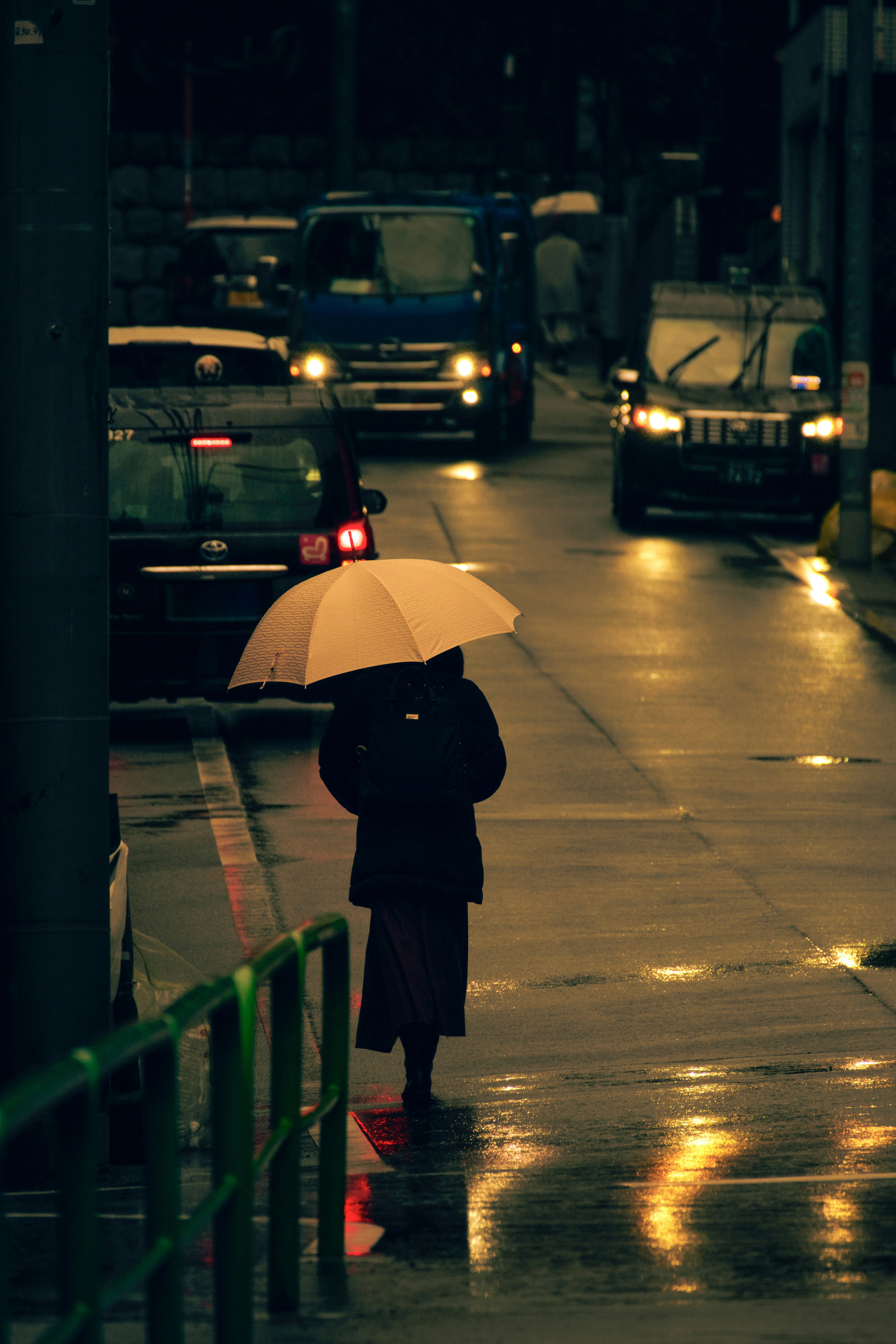 雨の朝の氷川坂で傘をさす人のある街並み