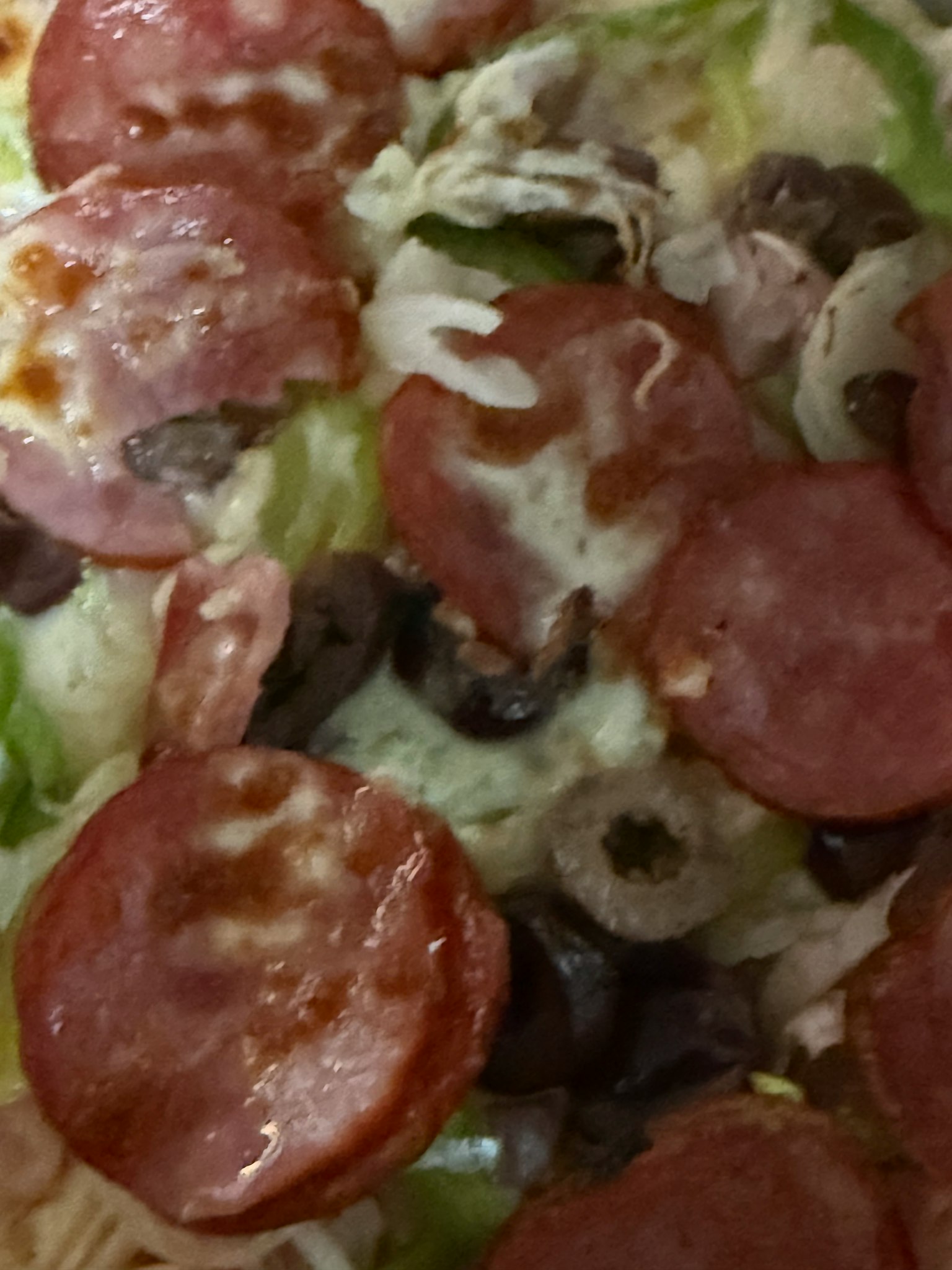 サラミとオリーブのトッピングが施されたピザのクローズアップ