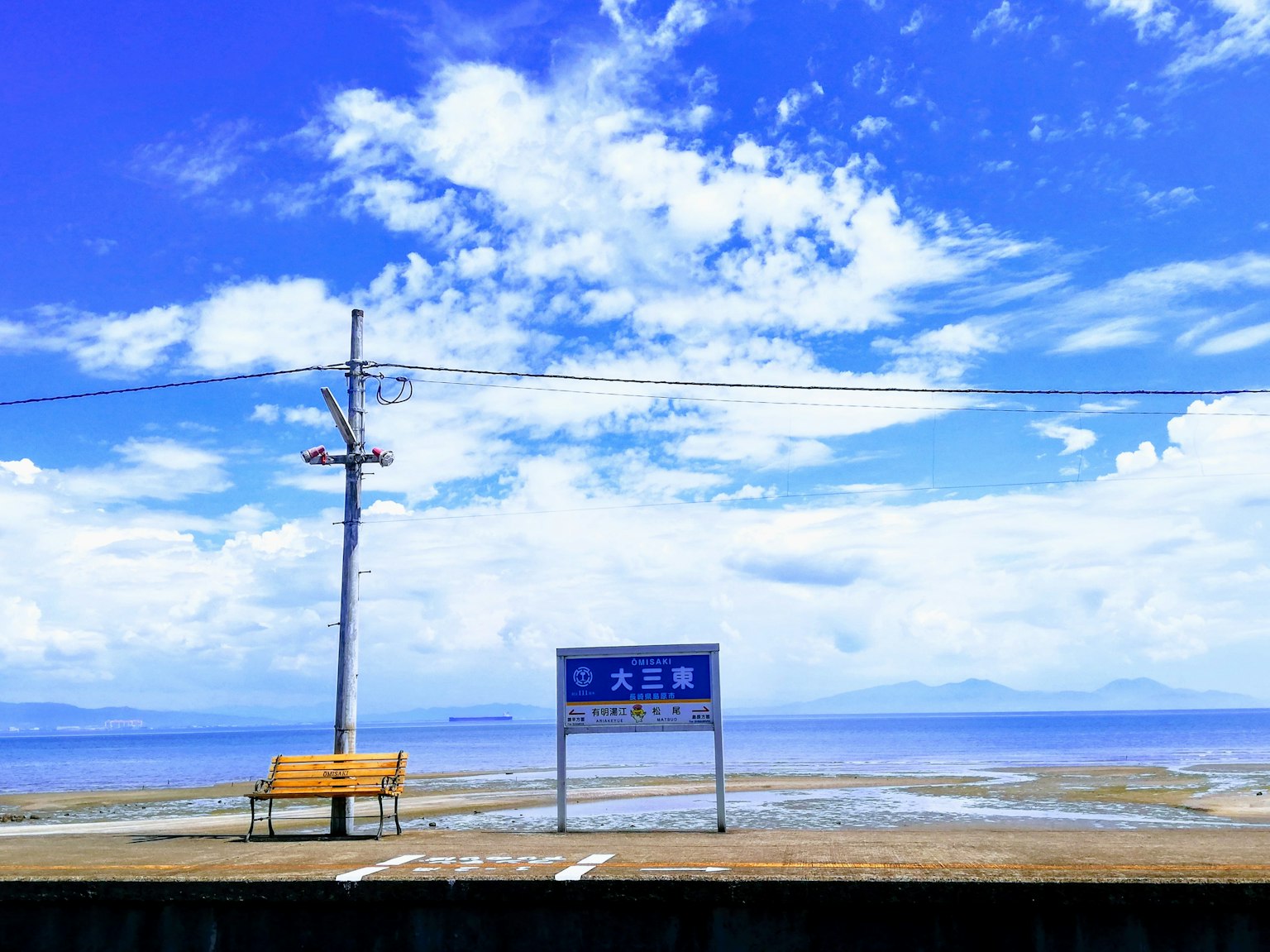 海岸風景，藍天和雲彩，帶有長椅和標誌