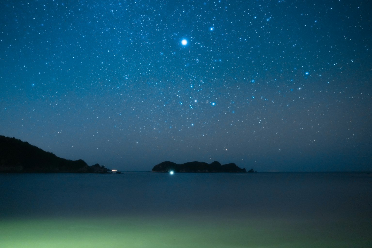 Langit malam dipenuhi bintang di atas laut tenang