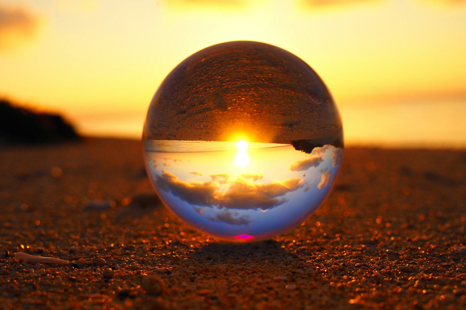 A crystal ball on the beach reflecting a beautiful sunset