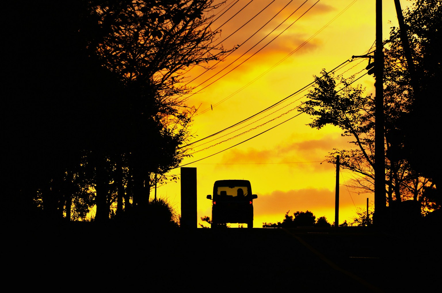 Silhouette eines Autos vor einem lebhaften Sonnenuntergang