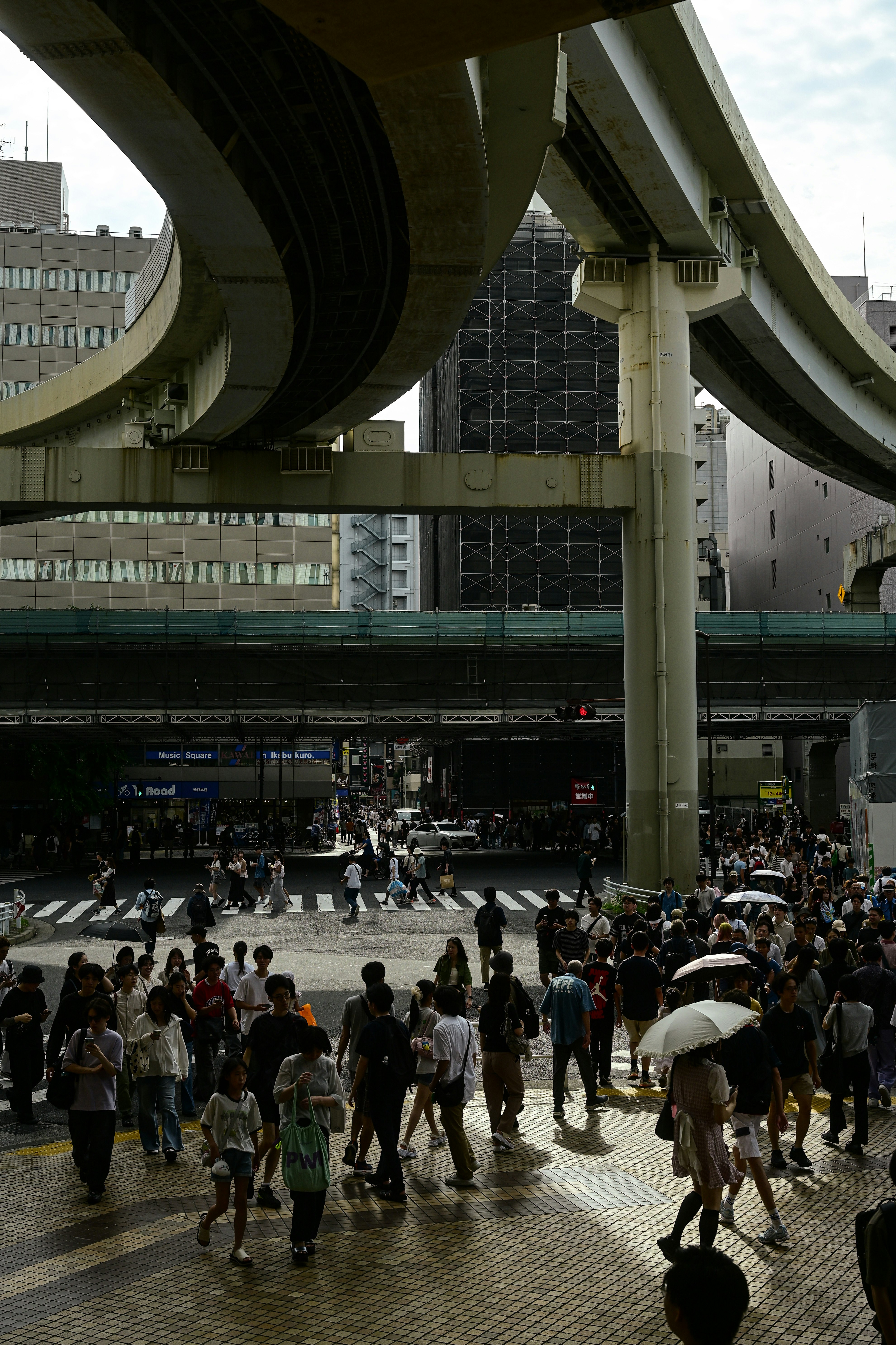 池袋の駅構内で傘をさす人々と高架の通路