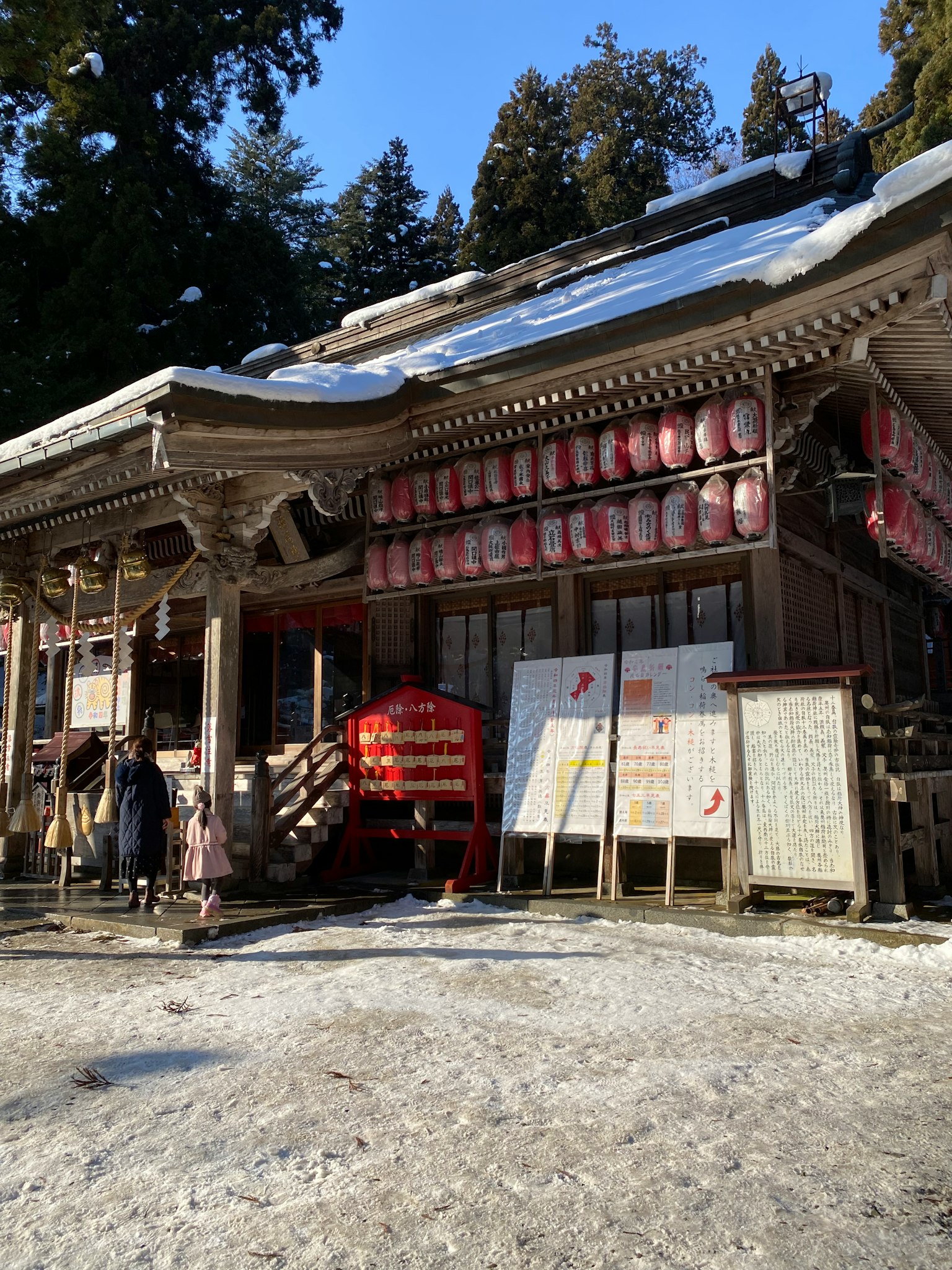 被雪覆蓋的神社外觀有紅色燈籠和標誌