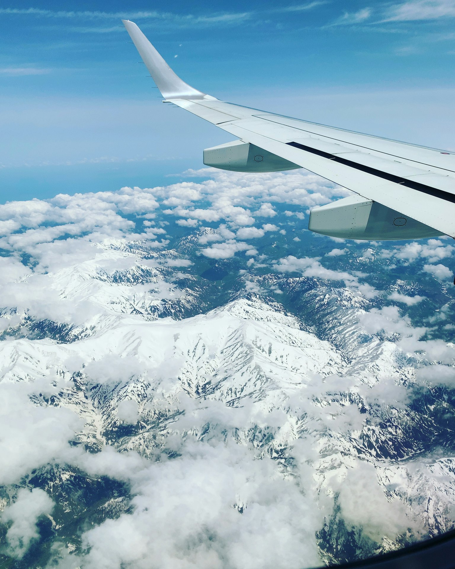 Vista desde el ala de un avión sobre montañas nevadas y nubes