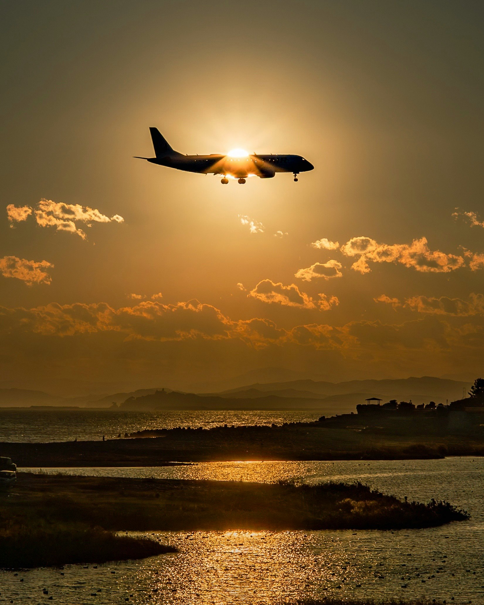 夕陽天空中飛過的飛機與海岸景色