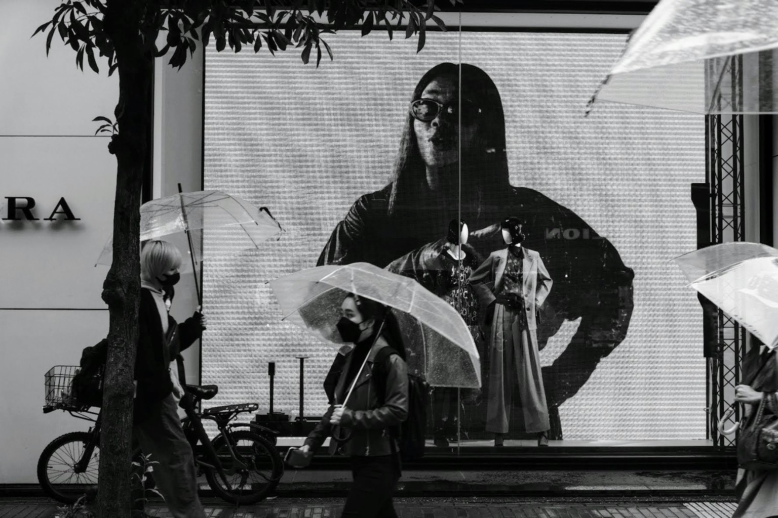 Femme affichée dans une vitrine avec des piétons tenant des parapluies