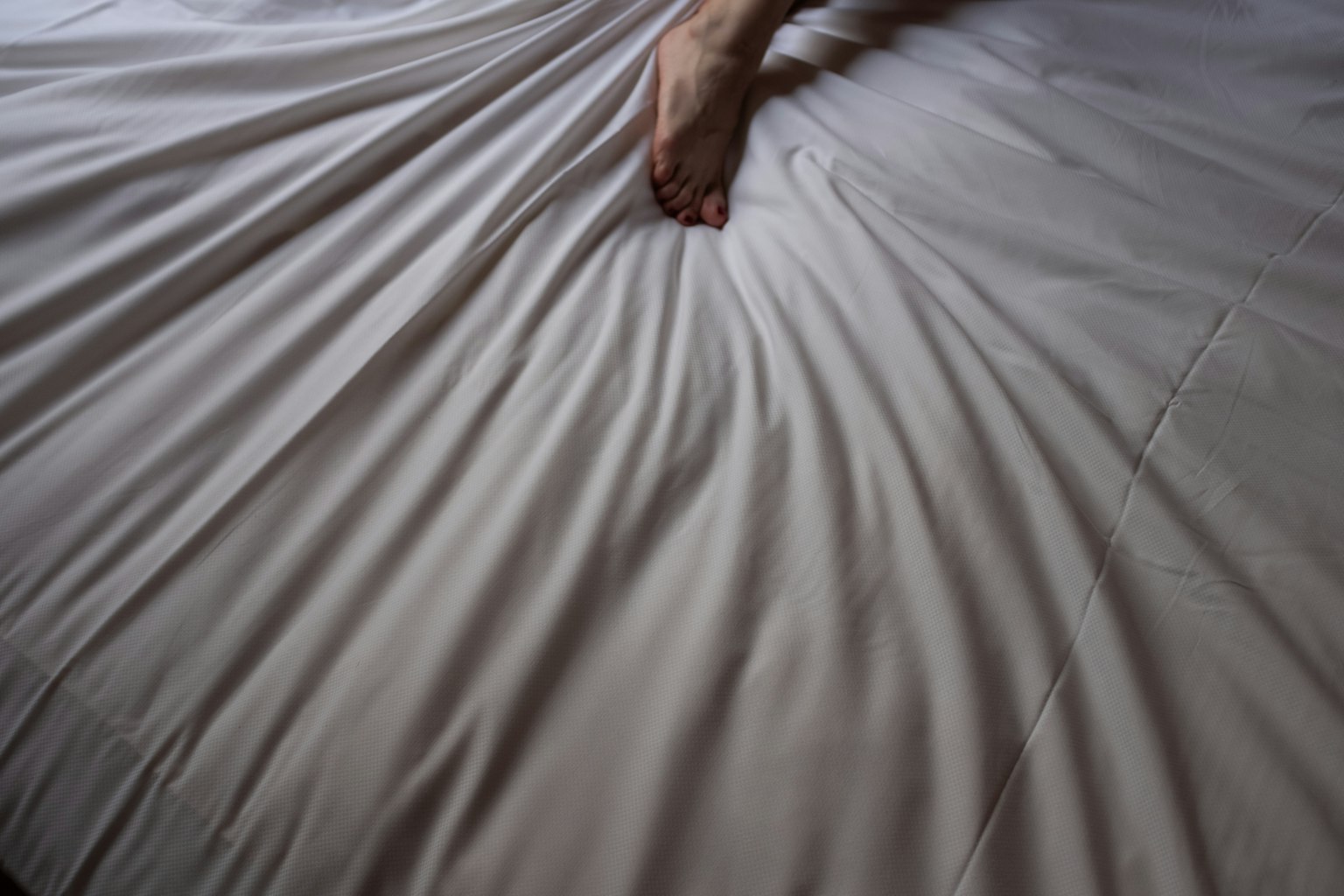 Chân resting trên ga trải giường nhăn