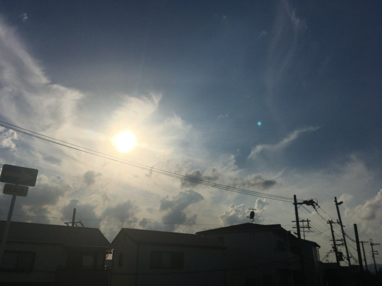 Un paesaggio con un sole luminoso che brilla in un cielo blu pieno di nuvole