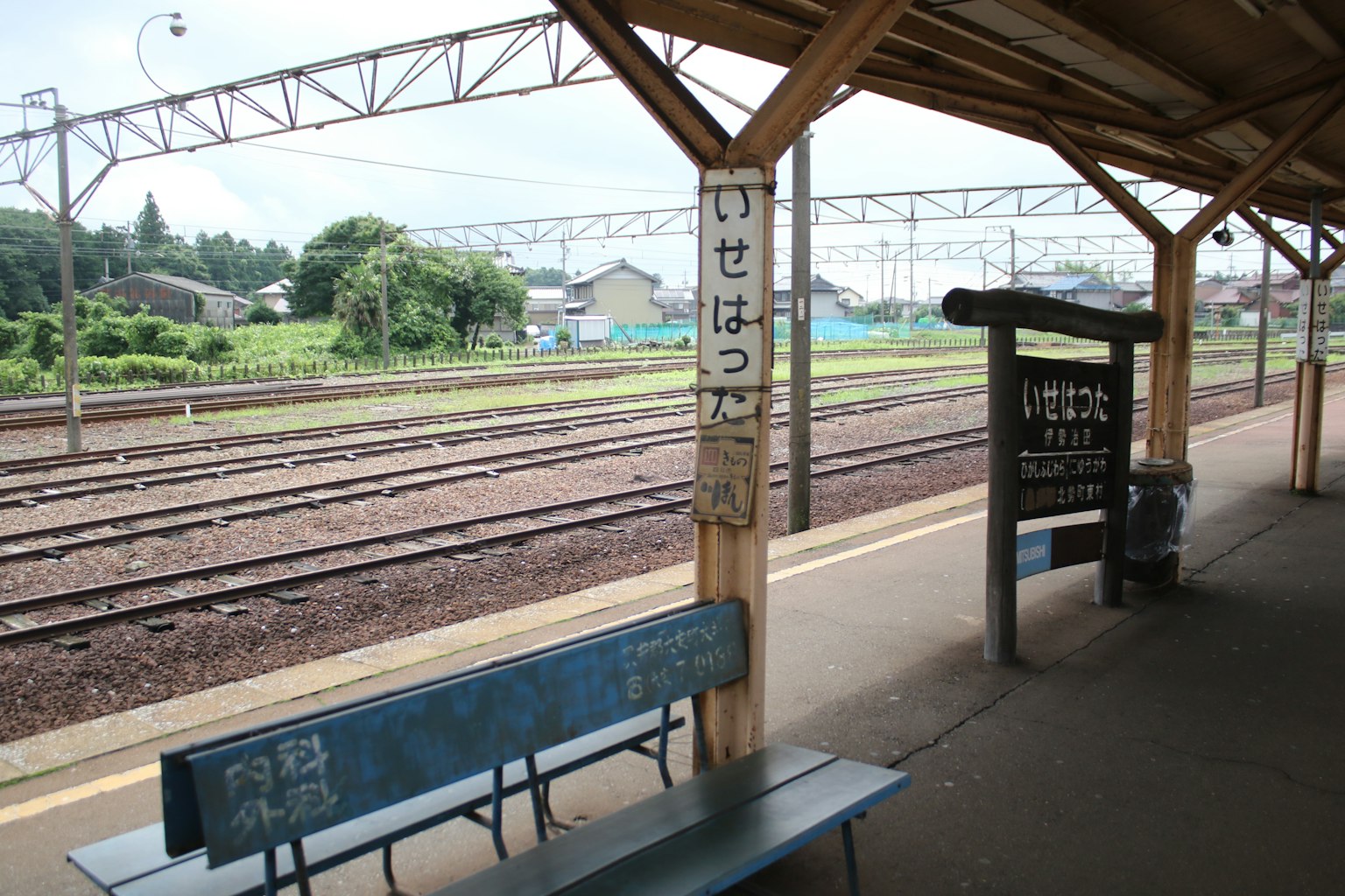 Blue bench on the platform of Isehara Station with surrounding landscape