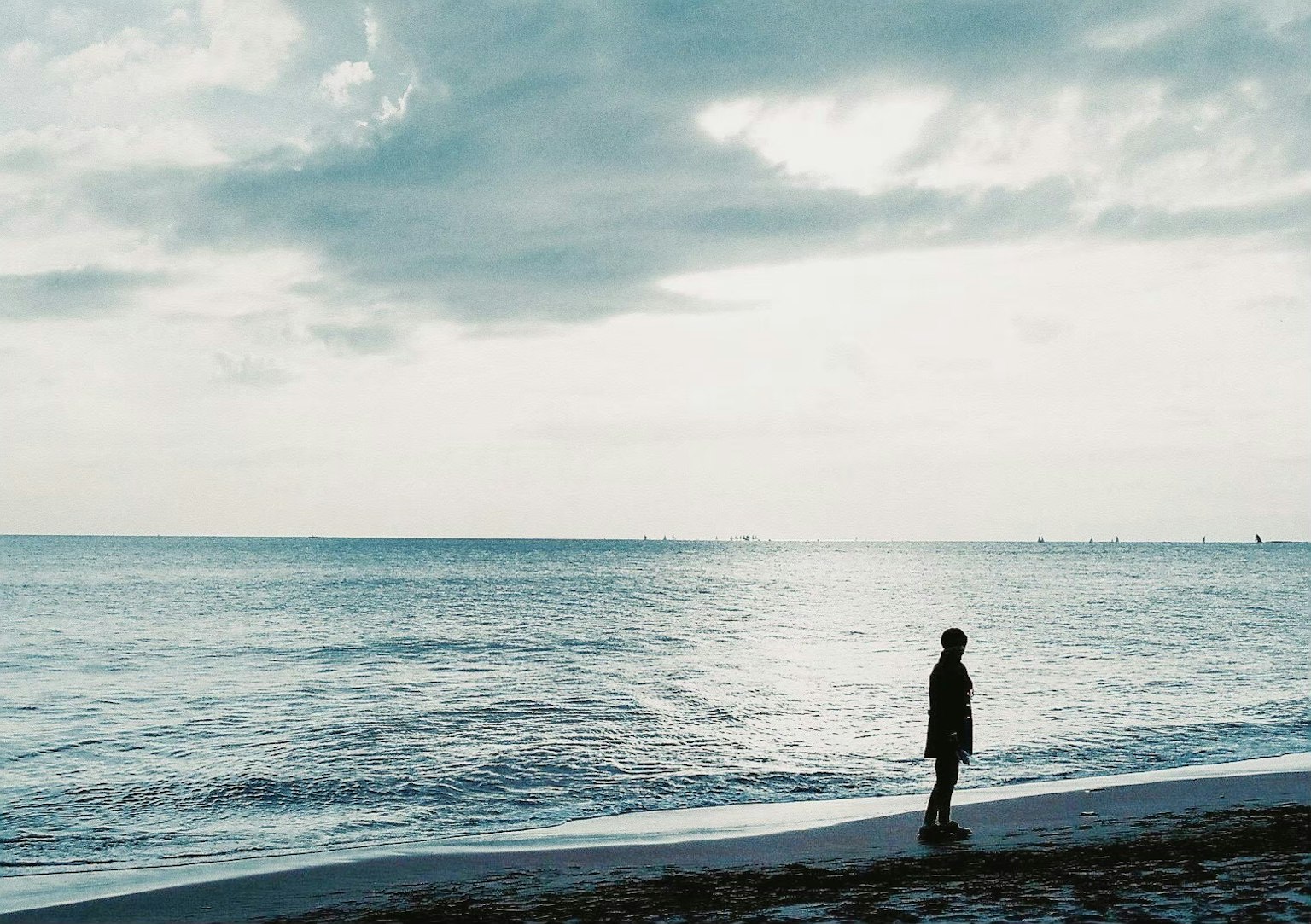 海滩上静静站着的人物与广阔的蓝色海洋