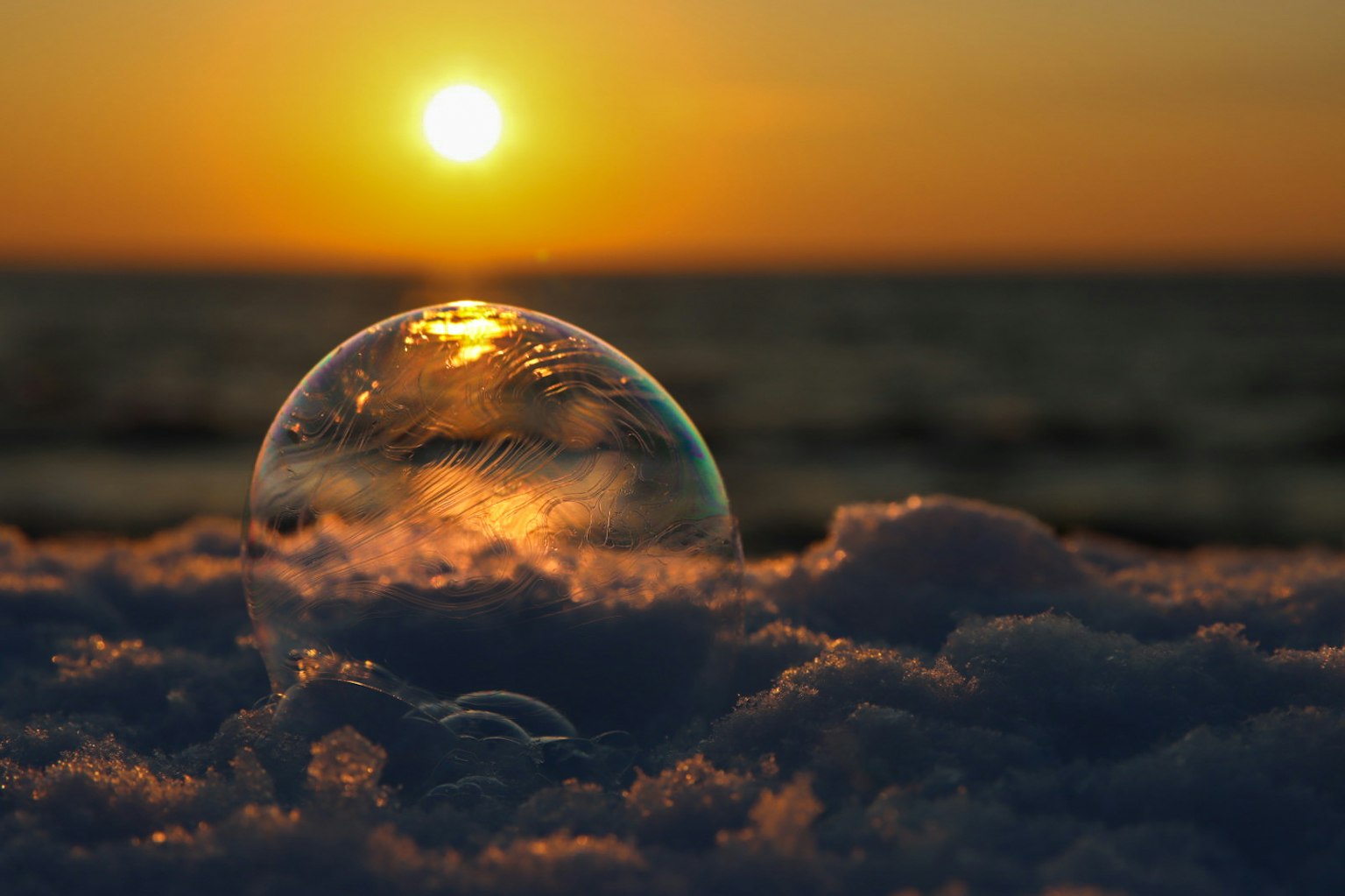Une bulle reposant sur la neige avec un coucher de soleil qui se reflète