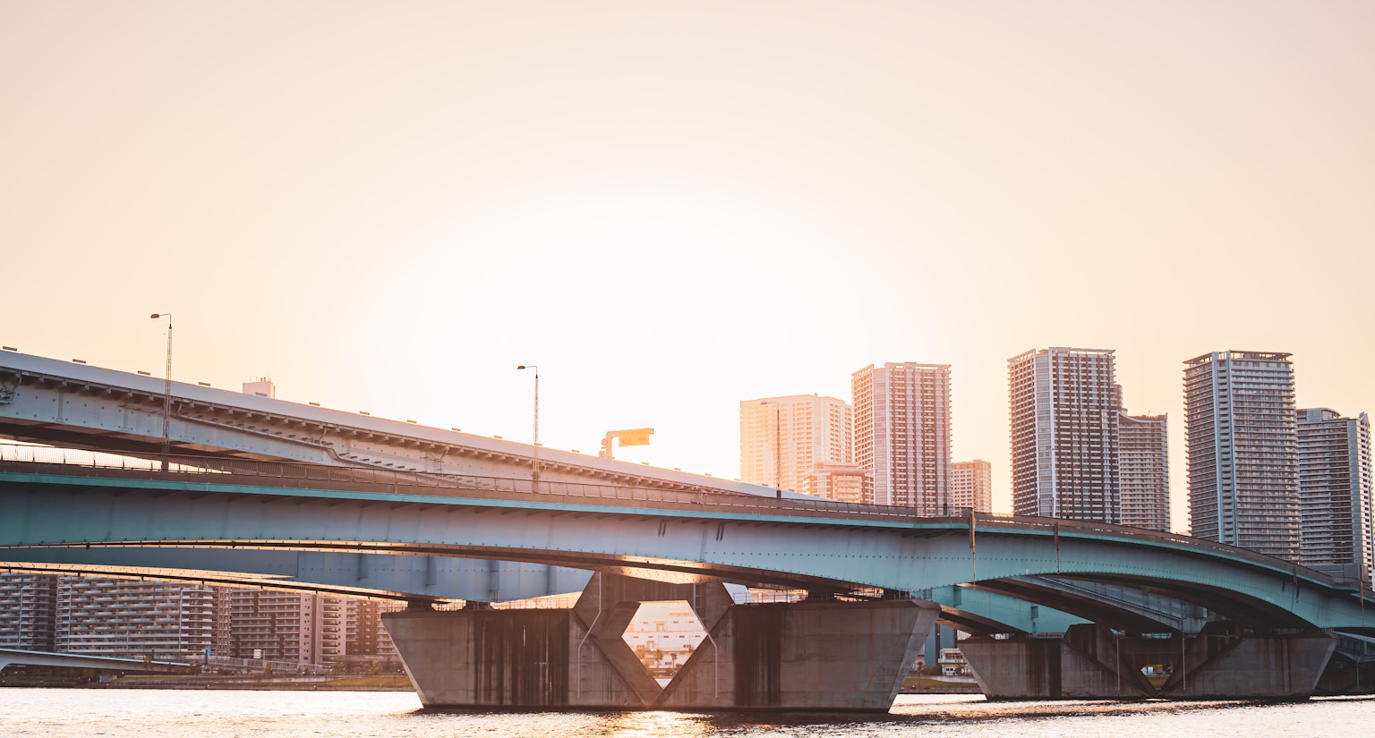 Brücke mit Sonnenuntergang im Hintergrund und Skyline hoher Gebäude