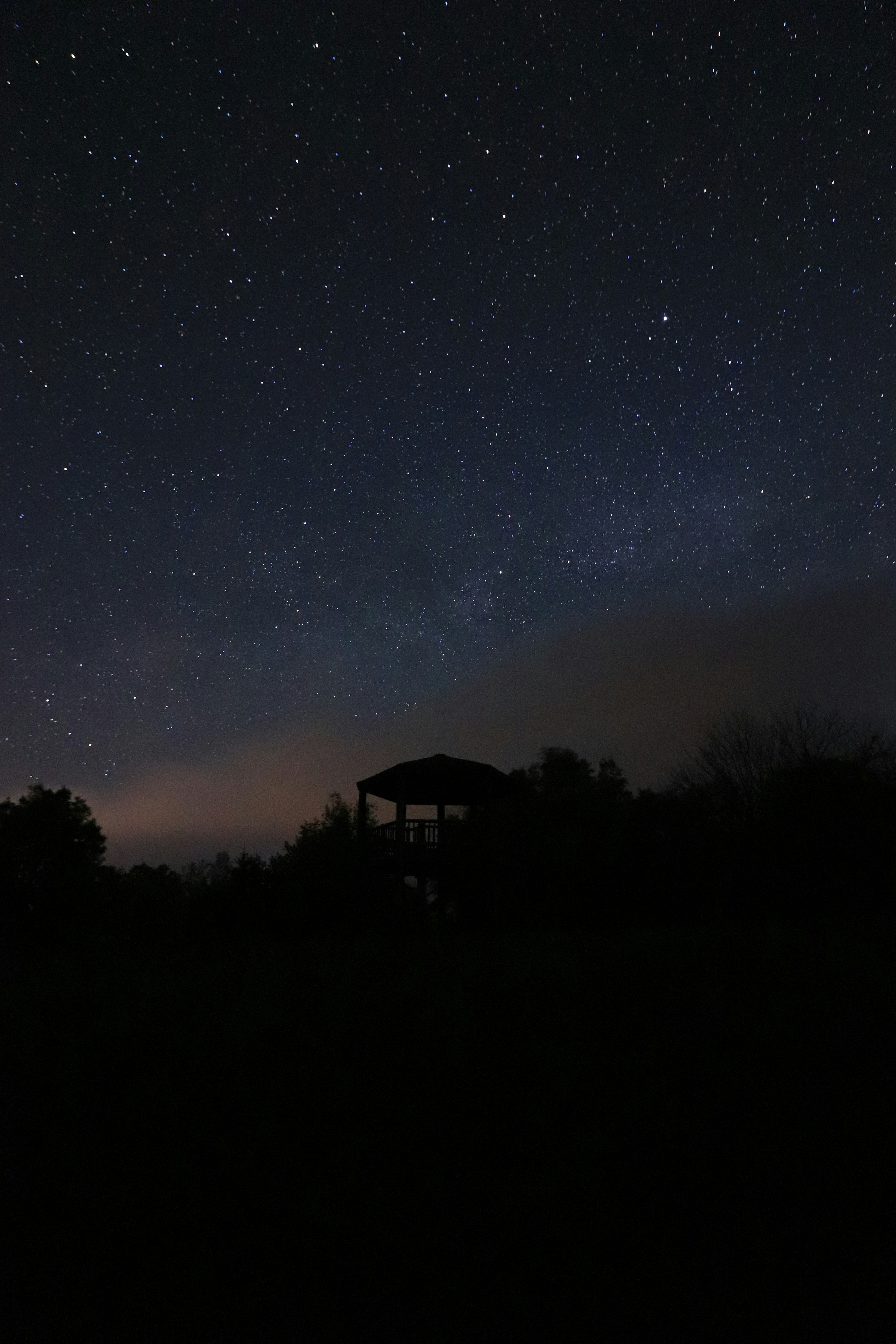 夜空に広がる星空とシルエットの展望台