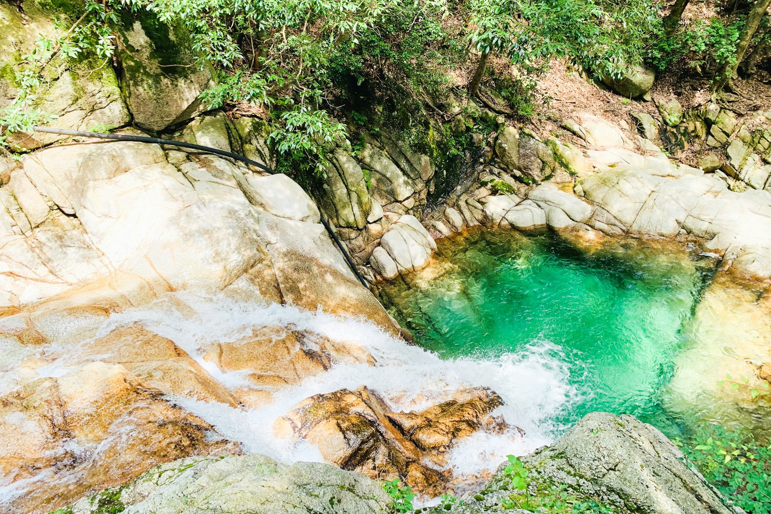Air terjun dengan air hijau jernih dan batuan di sekitarnya