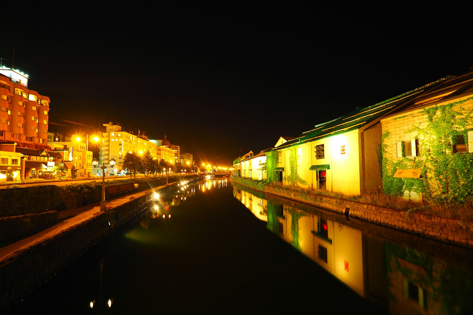 Canal de noche con edificios iluminados y reflejos