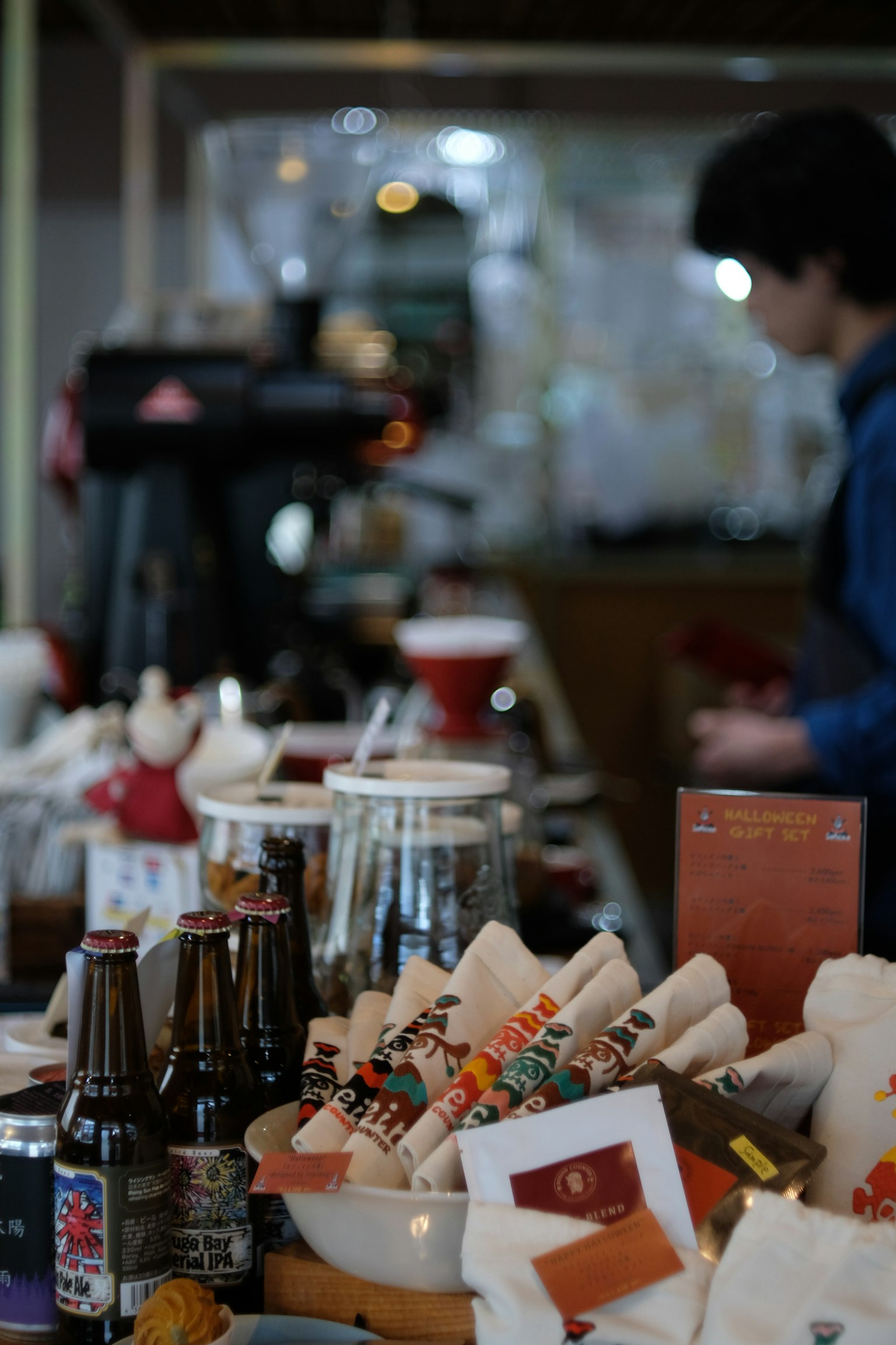 Exhibición de bebidas y alimentos en un mostrador de café con un miembro del personal trabajando