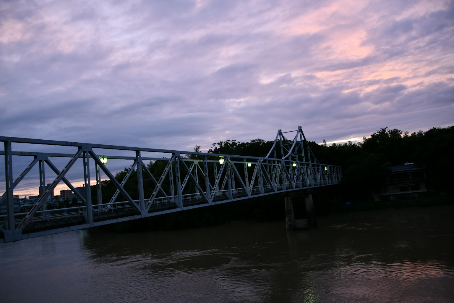 สะพานสีน้ำเงินข้ามแม่น้ำในยามพลบค่ำท่ามกลางท้องฟ้าที่มีเมฆ