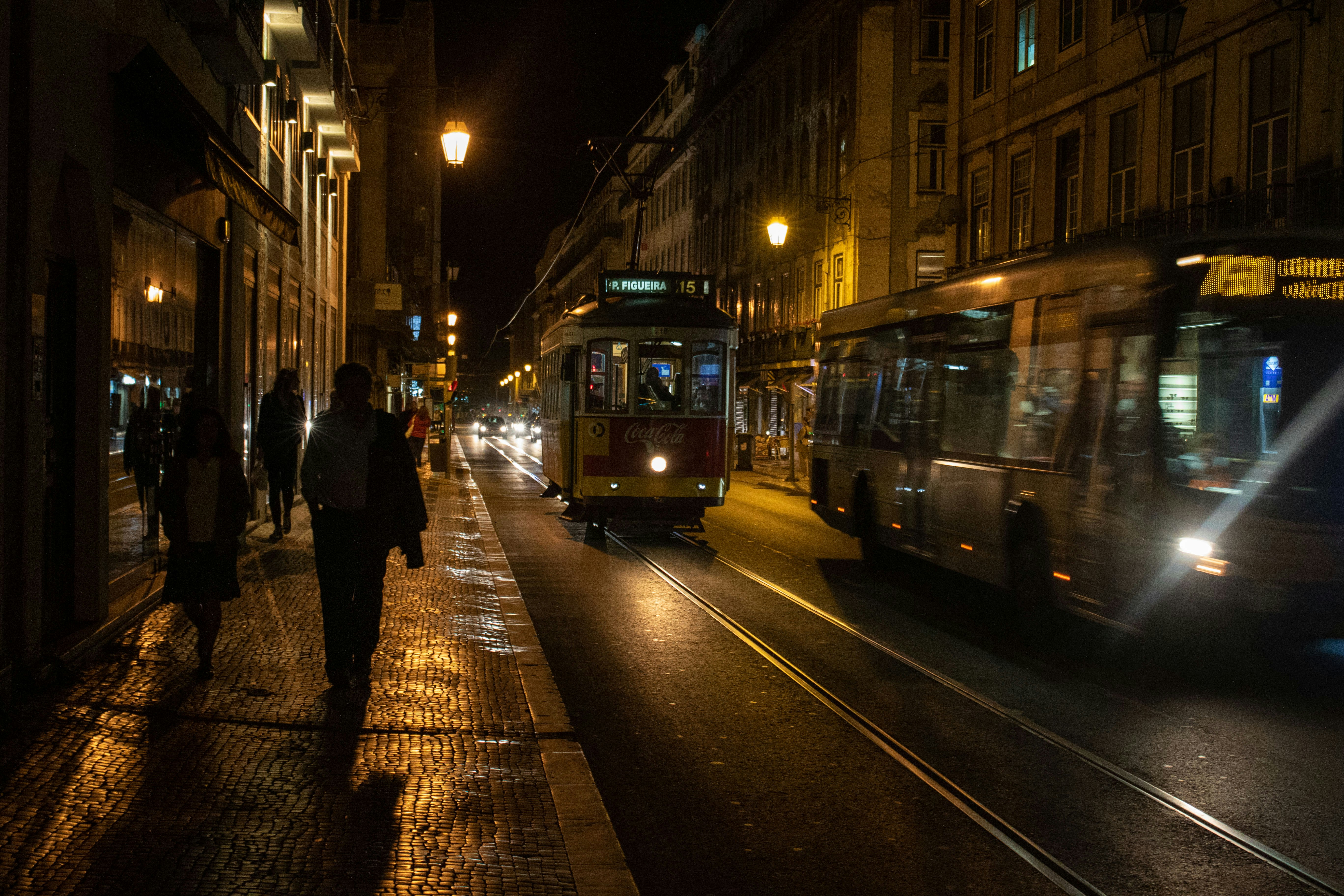 夜のリスボンの路地を走る路面電車と人影