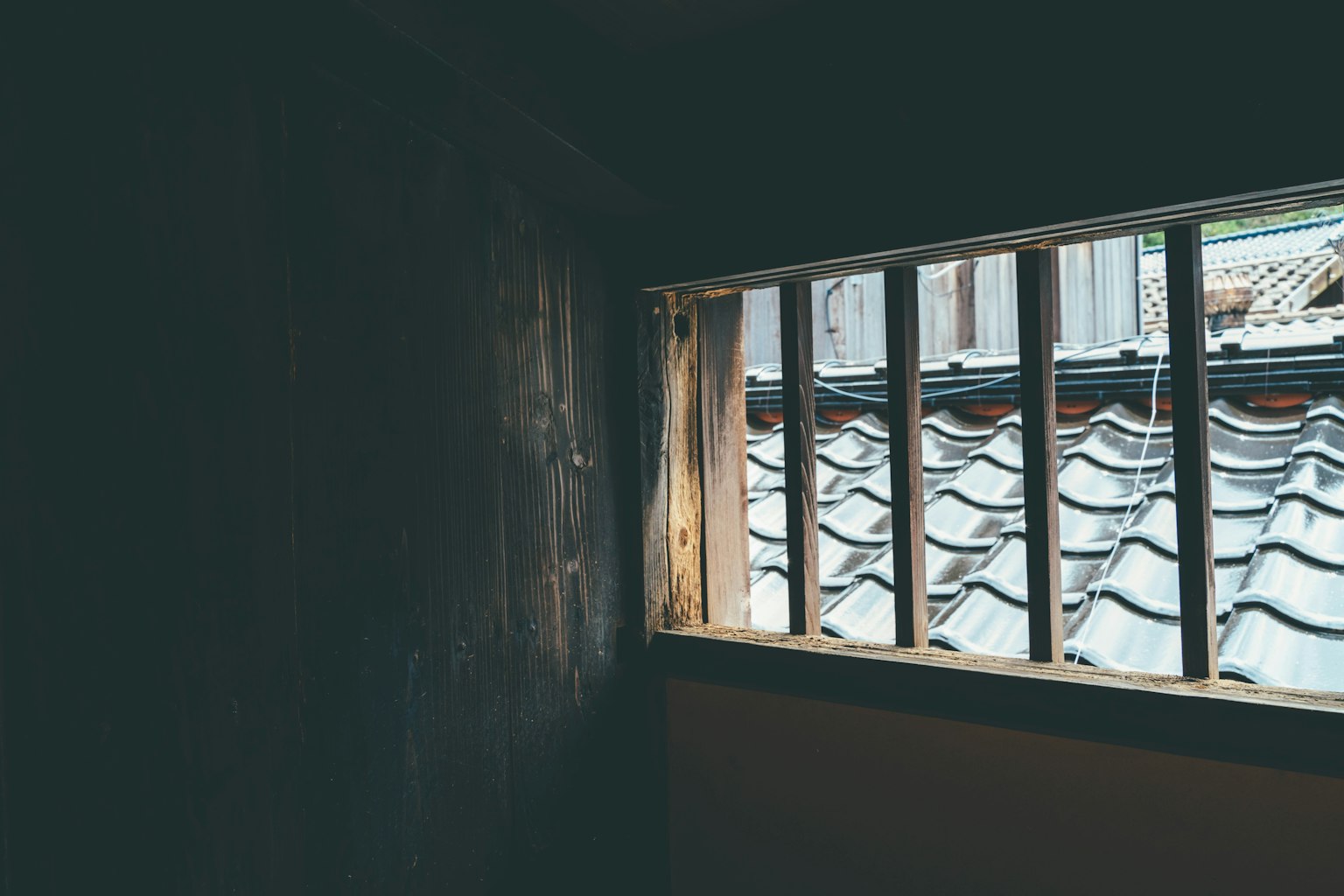 View of a traditional tiled roof through a window in a dimly lit room