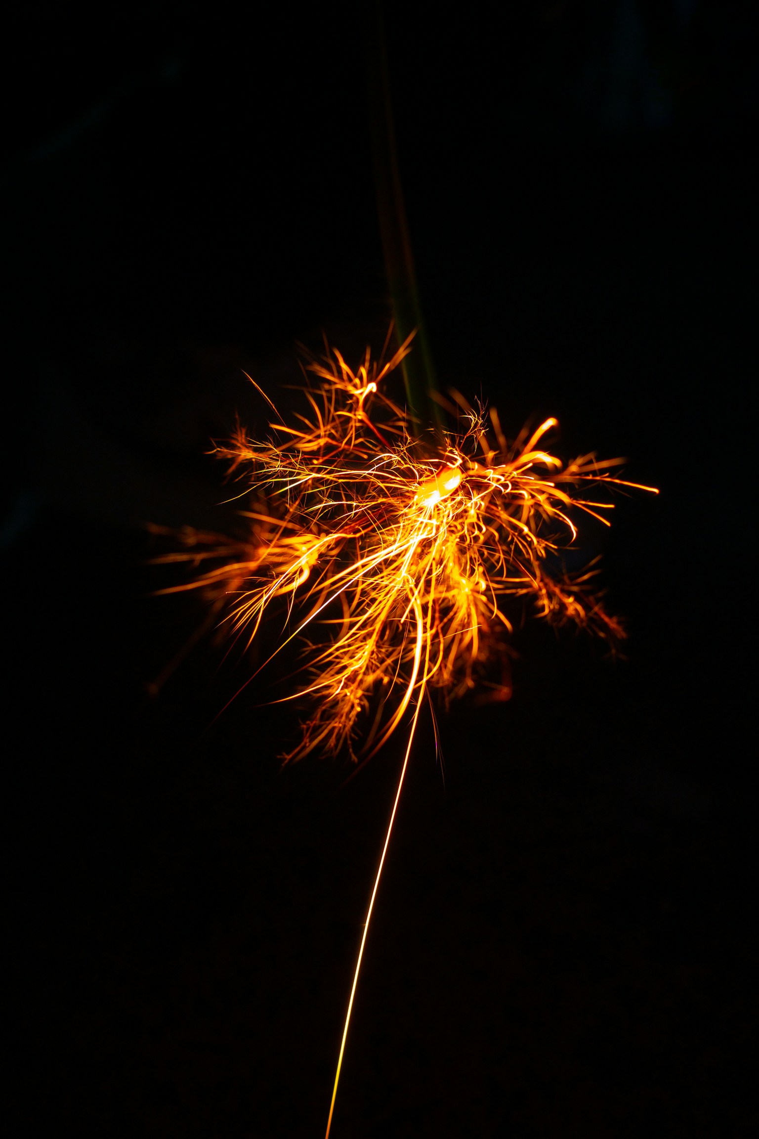 Sparkler emitting bright sparks against a dark background