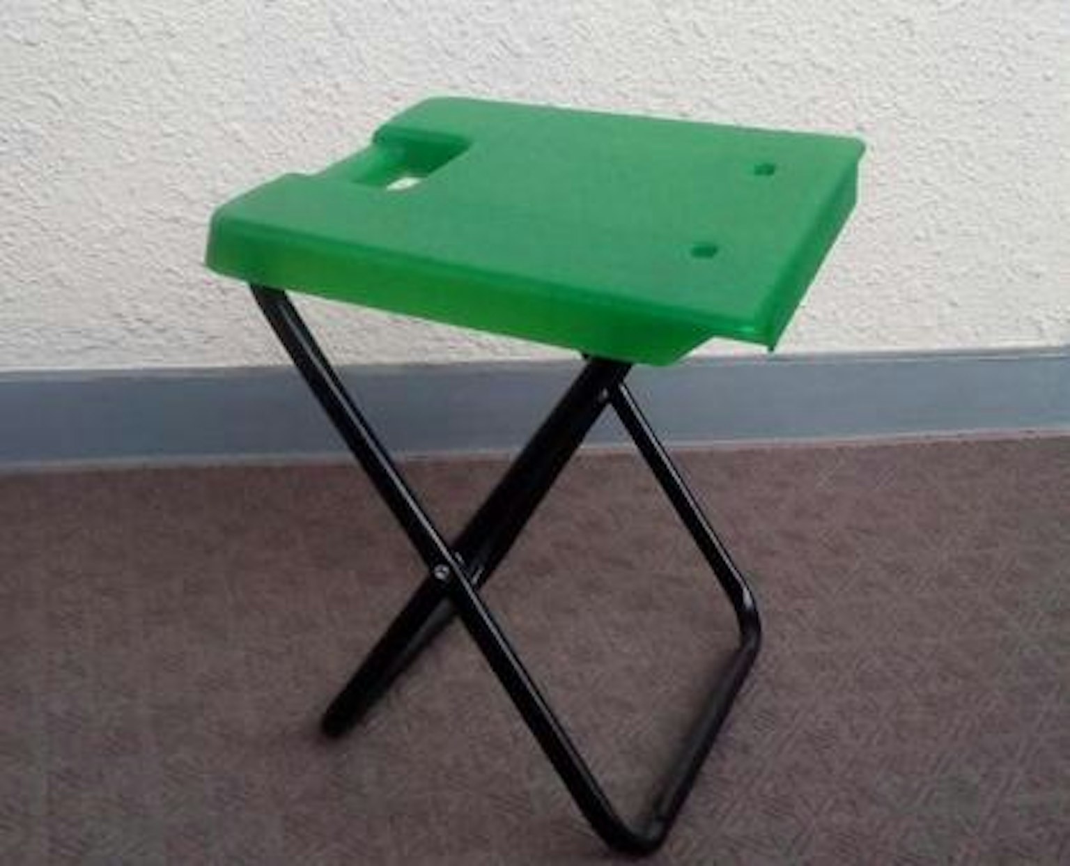 Green folding stool with black metal frame