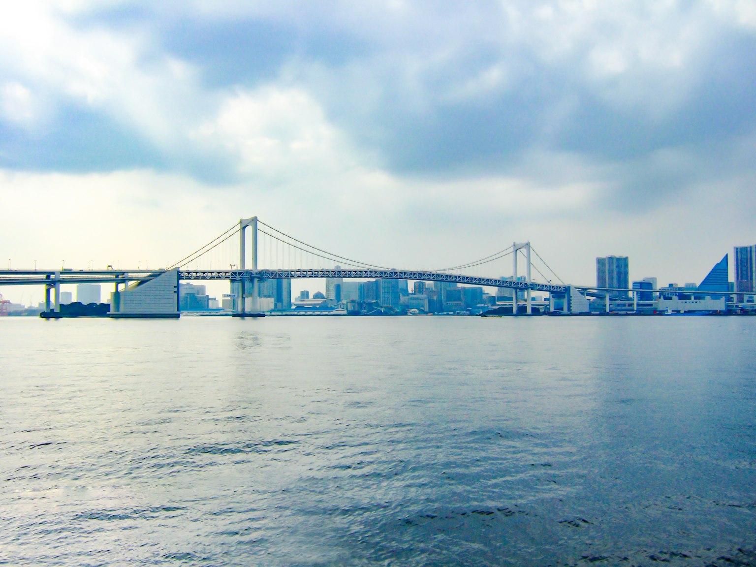 View of Rainbow Bridge with Tokyo skyline in the background over the water