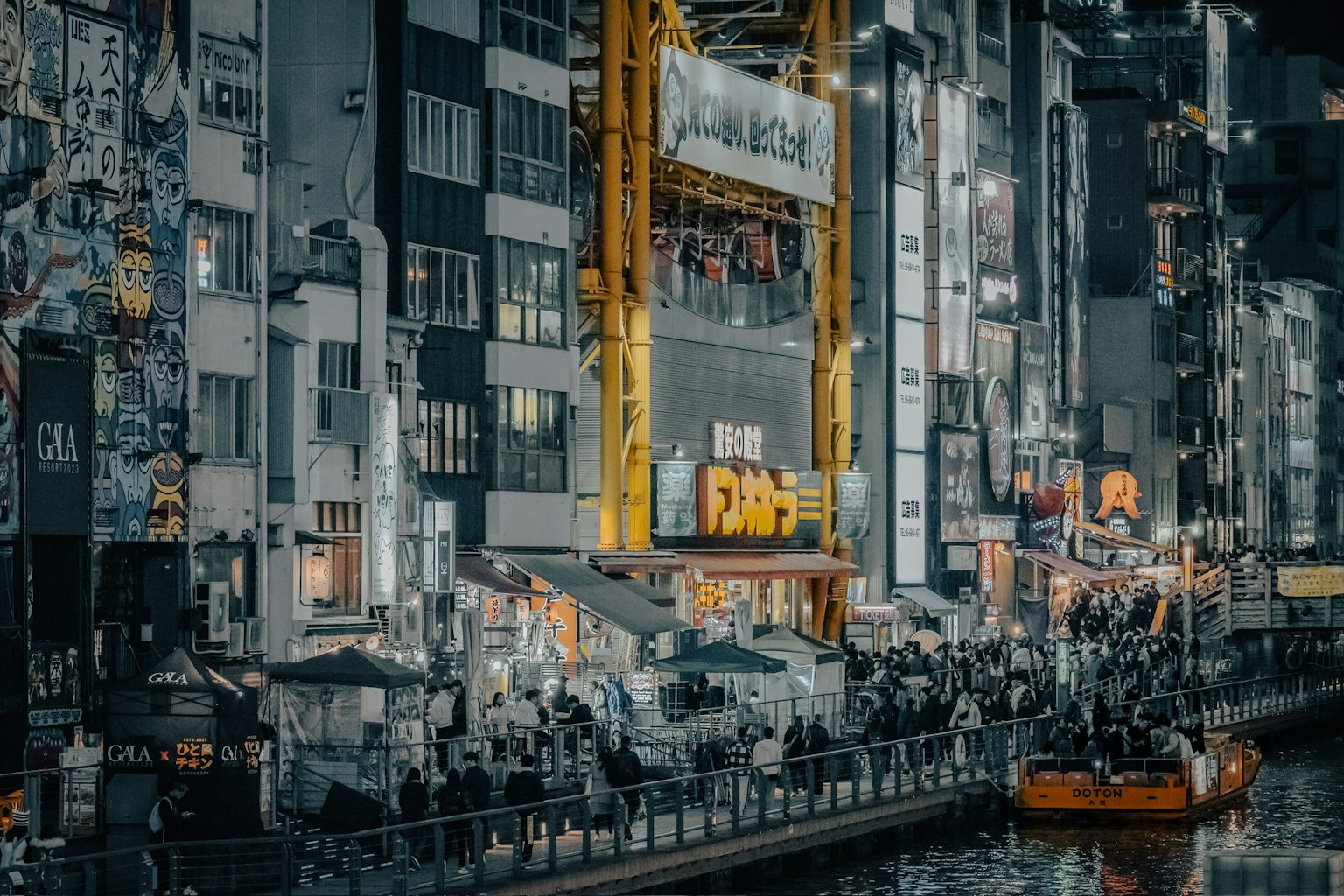 夜間河邊繁忙的攤位和城市景觀中的黃色起重機