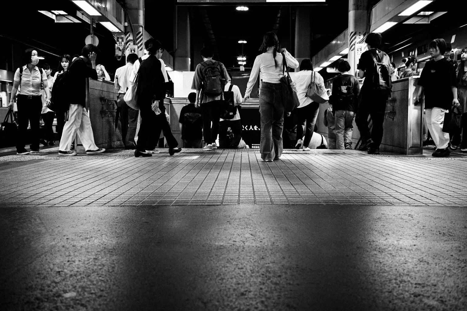Imagen en blanco y negro de personas moviéndose en una estación de tren