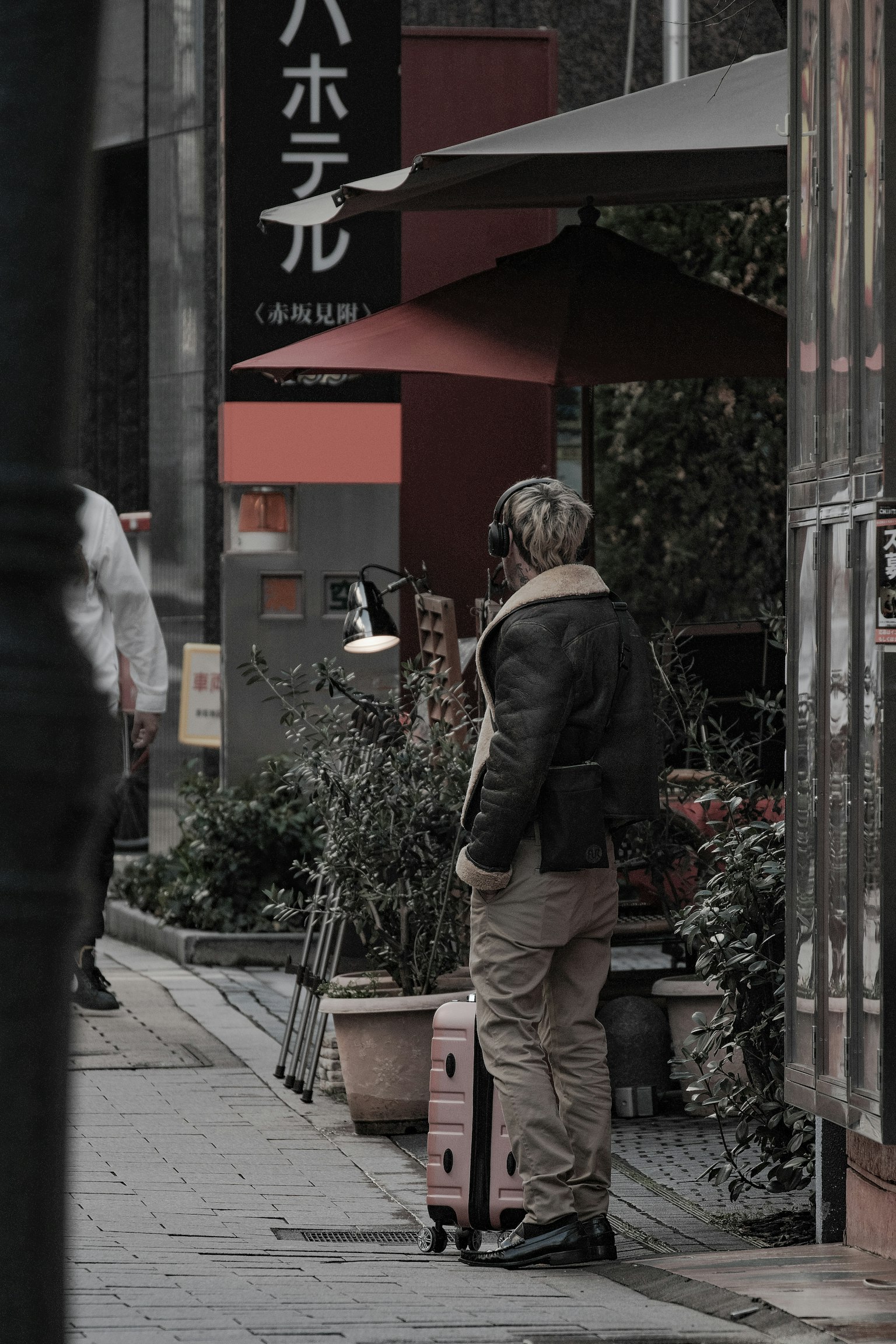 Traveler standing on city street with suitcase and surrounding greenery