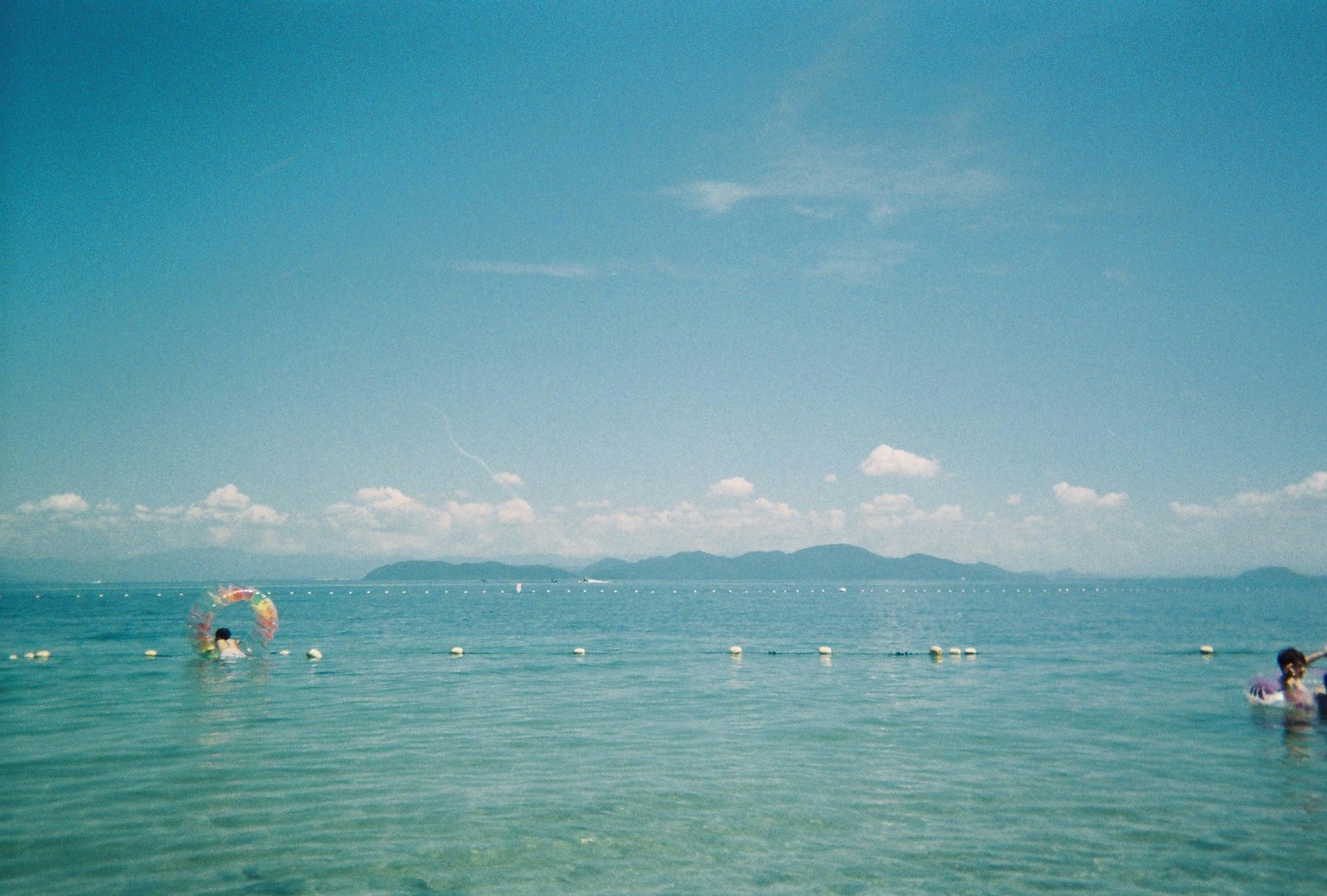海灘景觀，藍天和人們在水中游泳