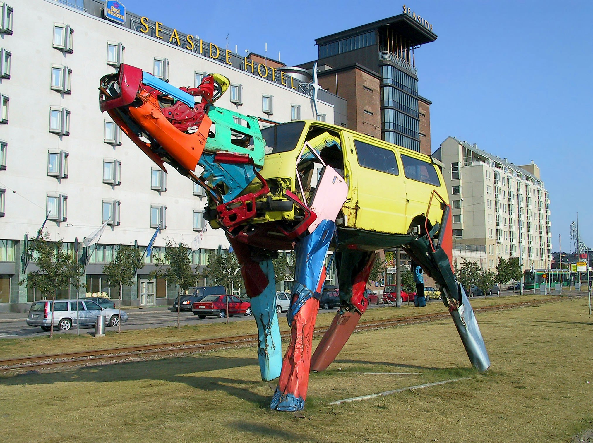 sculpture métallique colorée installée sur une place extérieure en pelouse