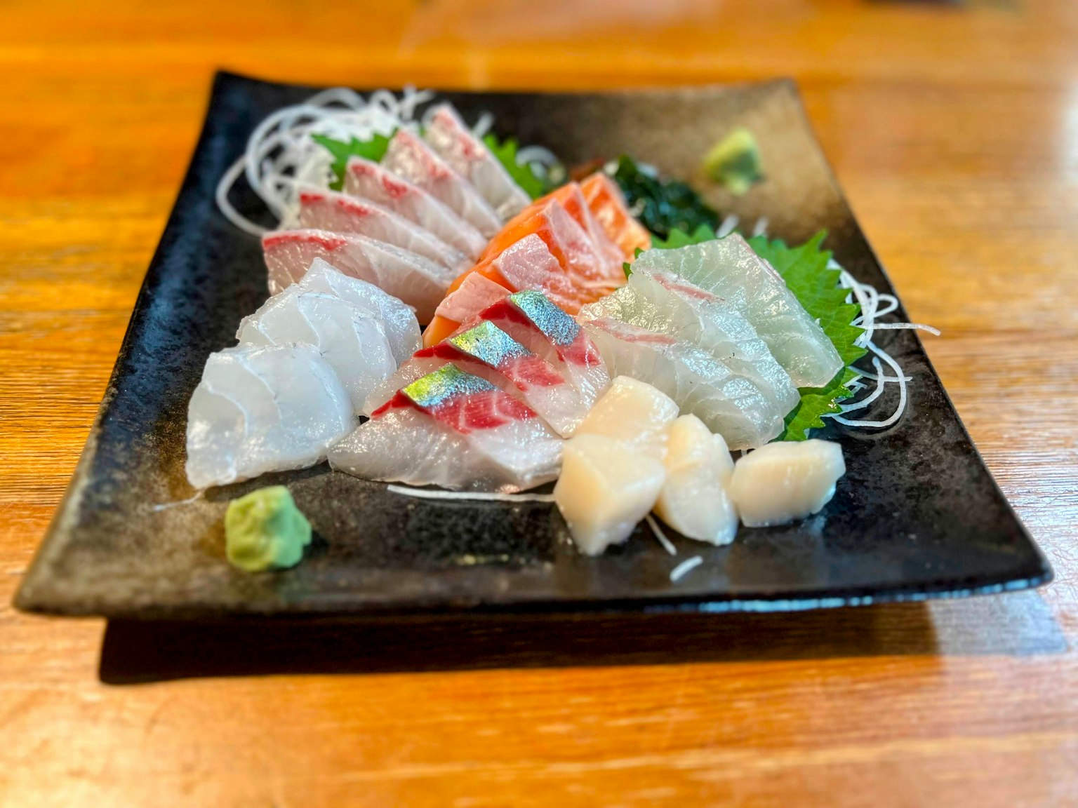 Plato de sashimi fresco servido en un plato negro