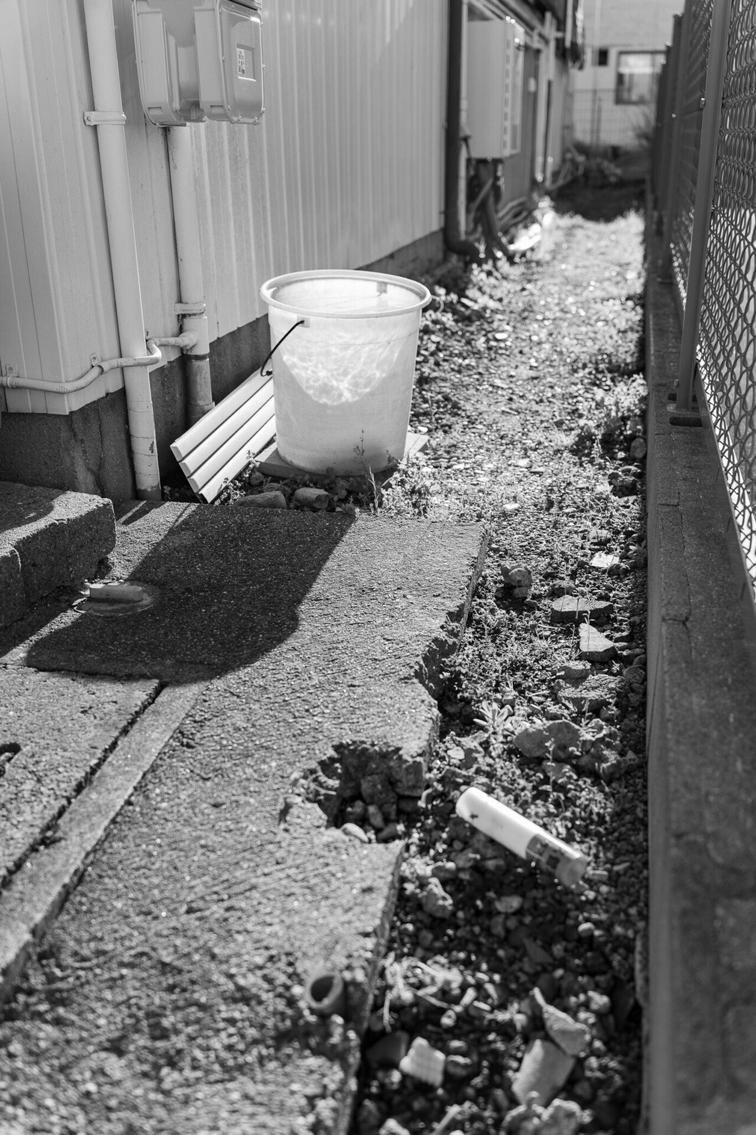 Narrow alley with a white bucket and scattered stones