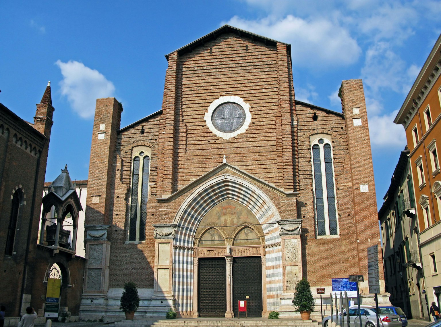 Façade d'une église avec des murs en briques brun rougeâtre fenêtre circulaire et entrée en arc