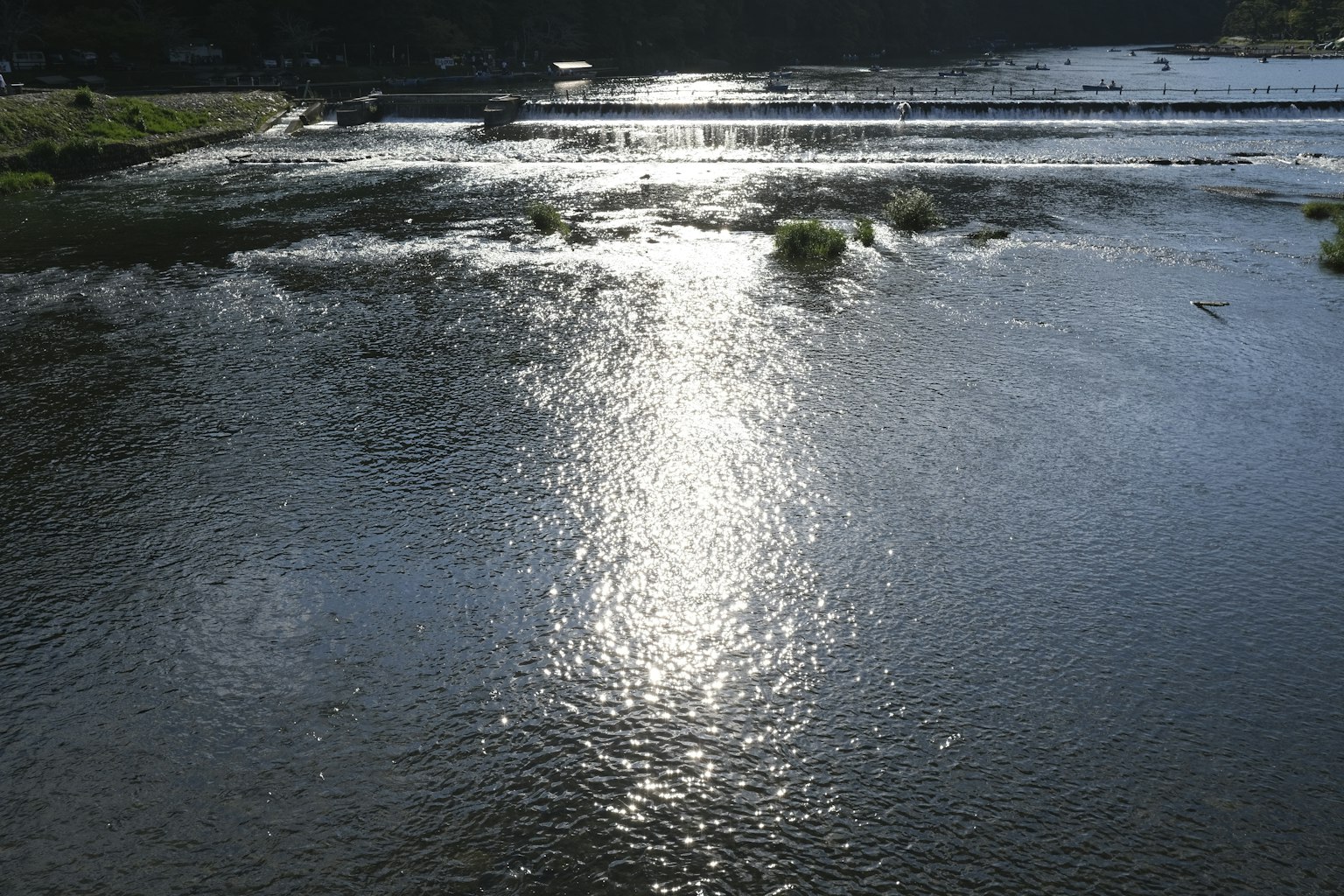 Superficie calma del fiume che riflette la luce con prato verde