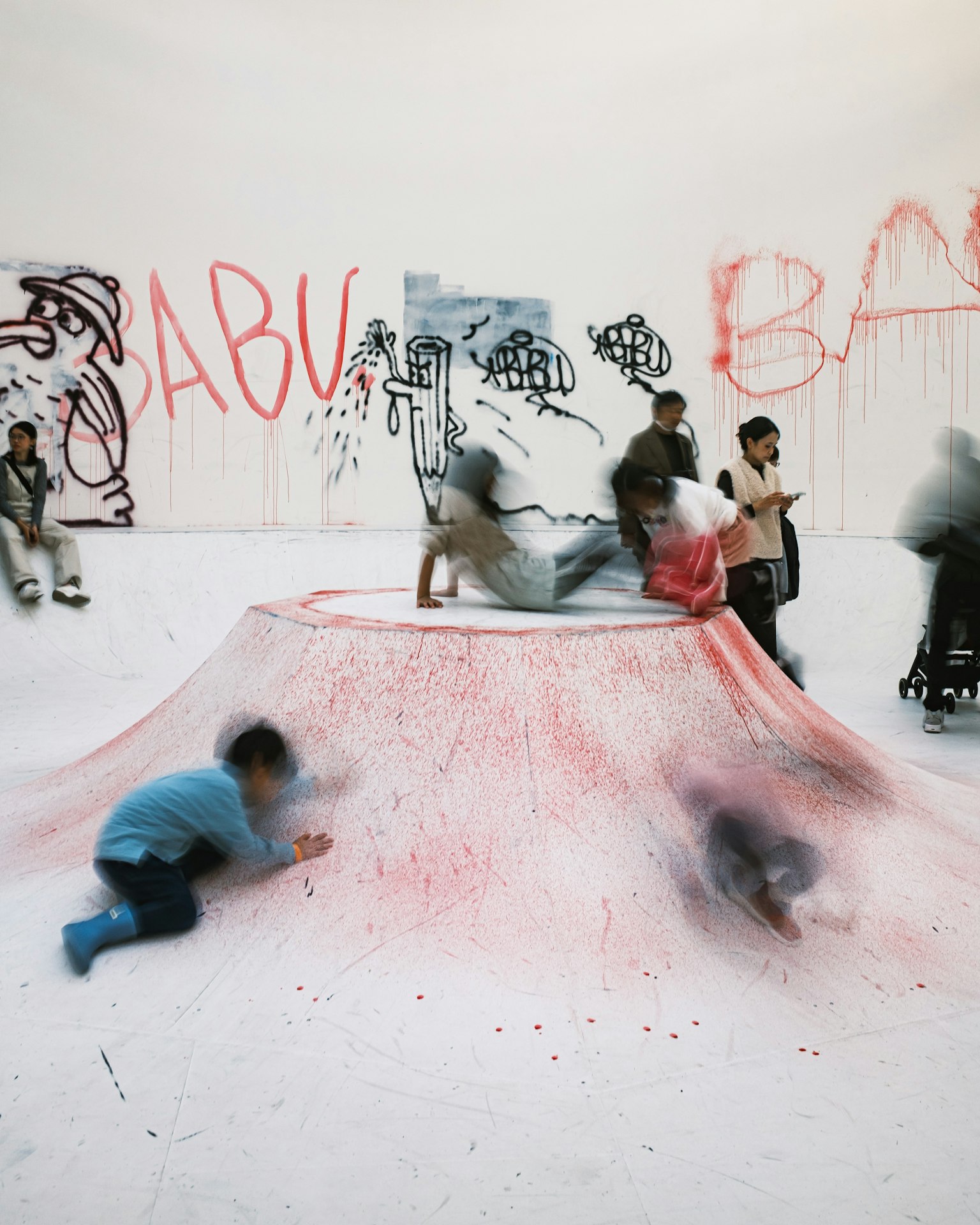 Niños jugando en un montículo de polvo rojo en una instalación artística con graffiti
