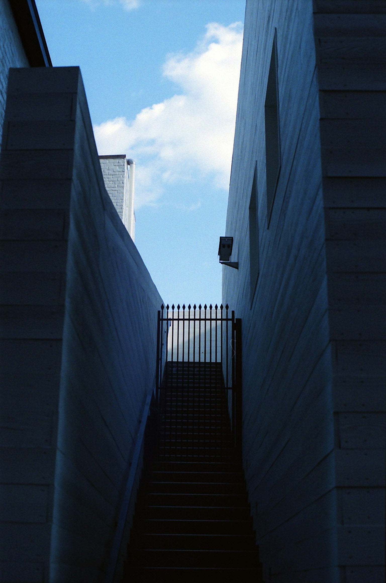 Immagine di un passaggio stretto con scale che portano verso un cielo blu